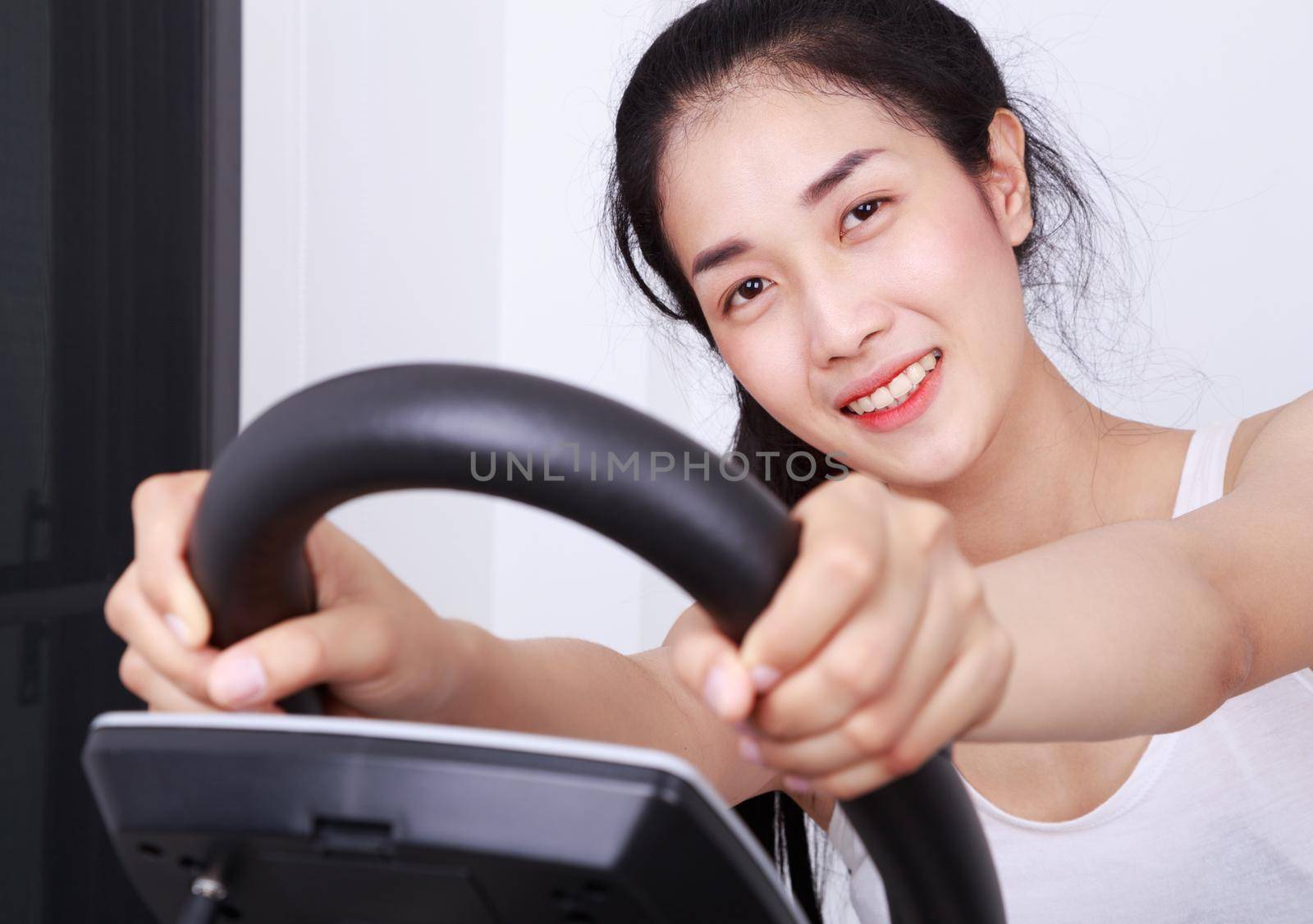 young sporty woman doing exercises with elliptical trainer