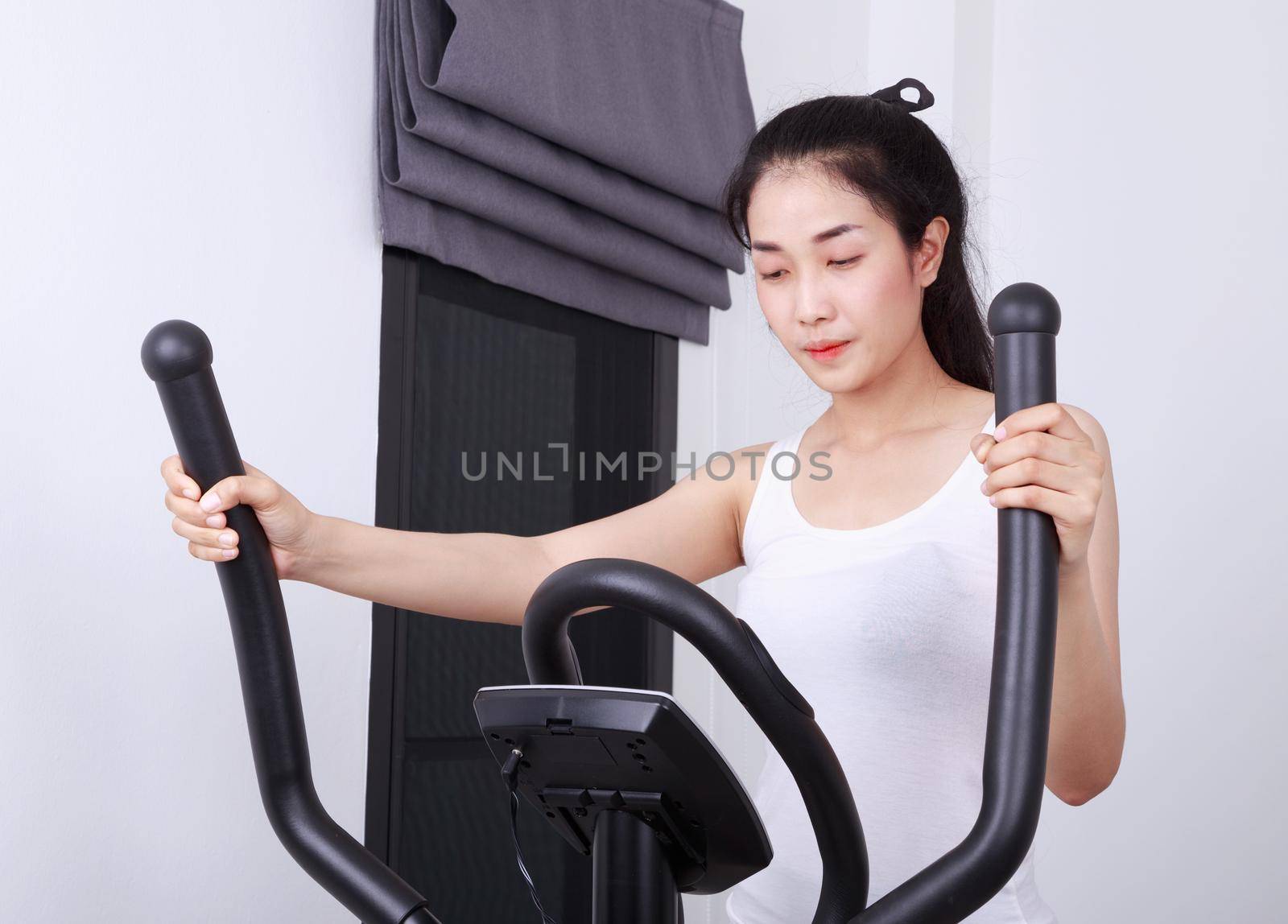 young sporty woman doing exercises with elliptical trainer