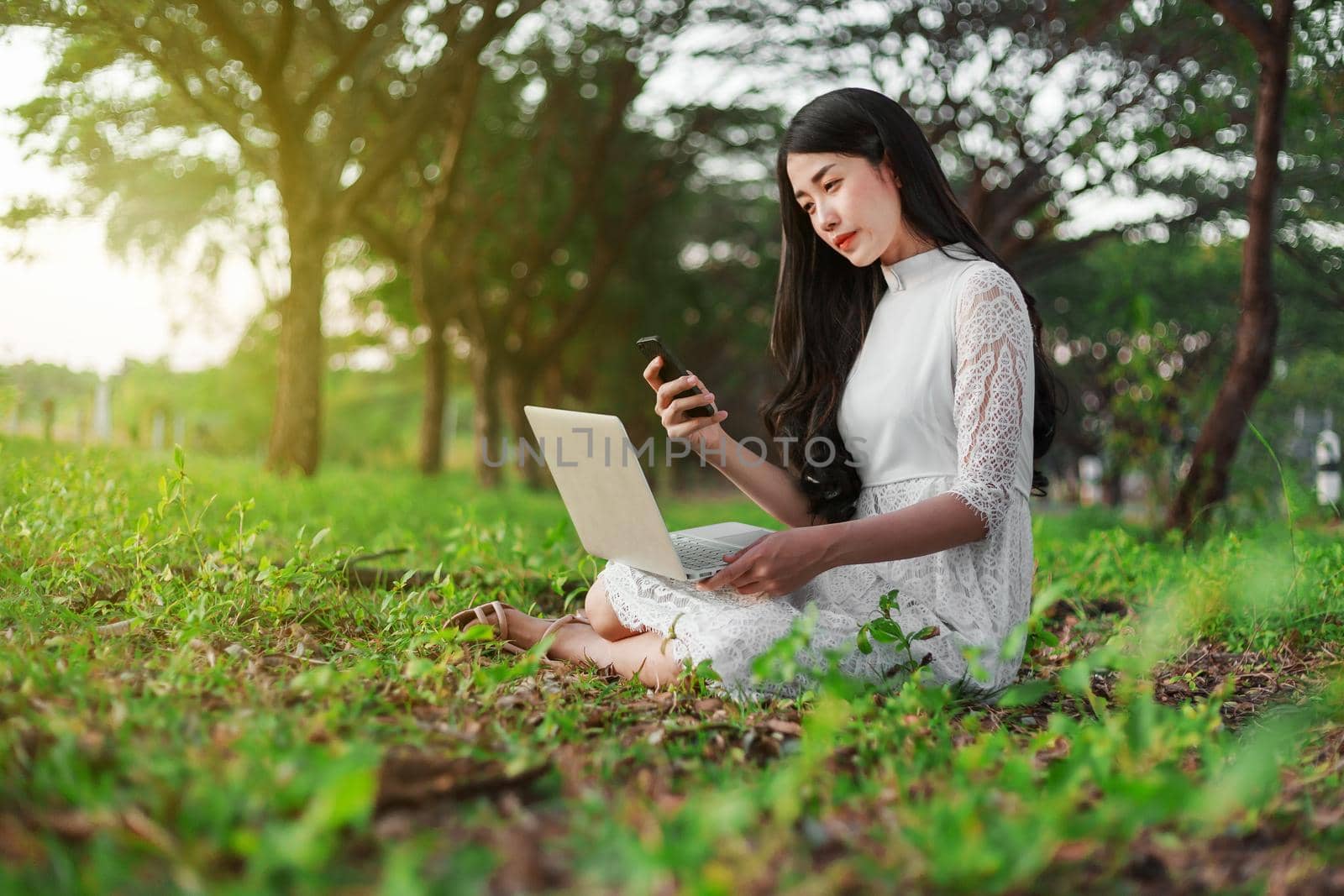 beautiful woman using laptop and mobile phone in the outdoor park