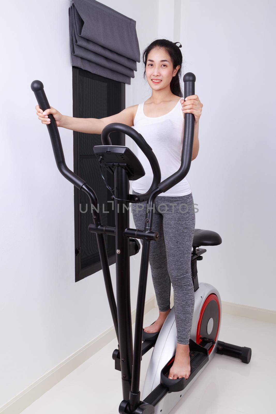 young sporty woman doing exercises with elliptical trainer