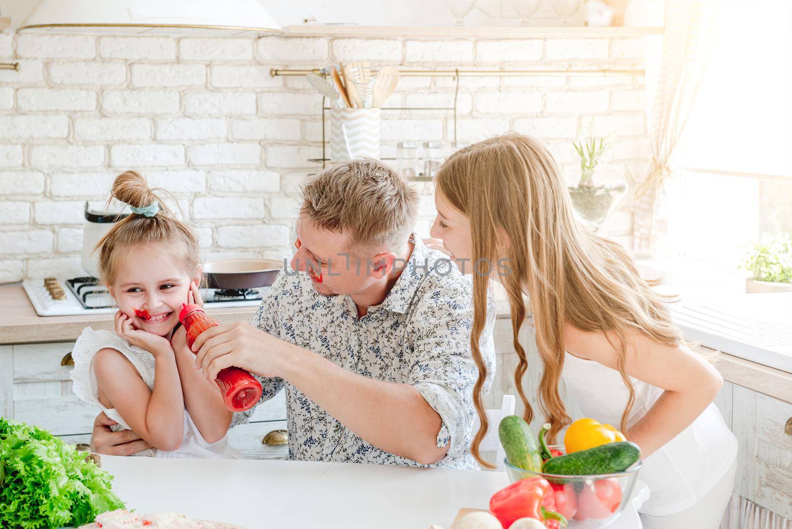 dad with two little daughters preparing pizza in the kitchen