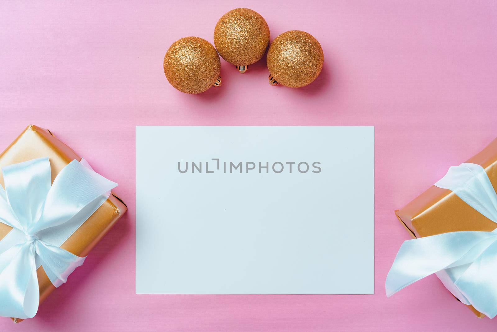 Christmas festive mock up with blank page, wrapped gifts and baubles on pink background