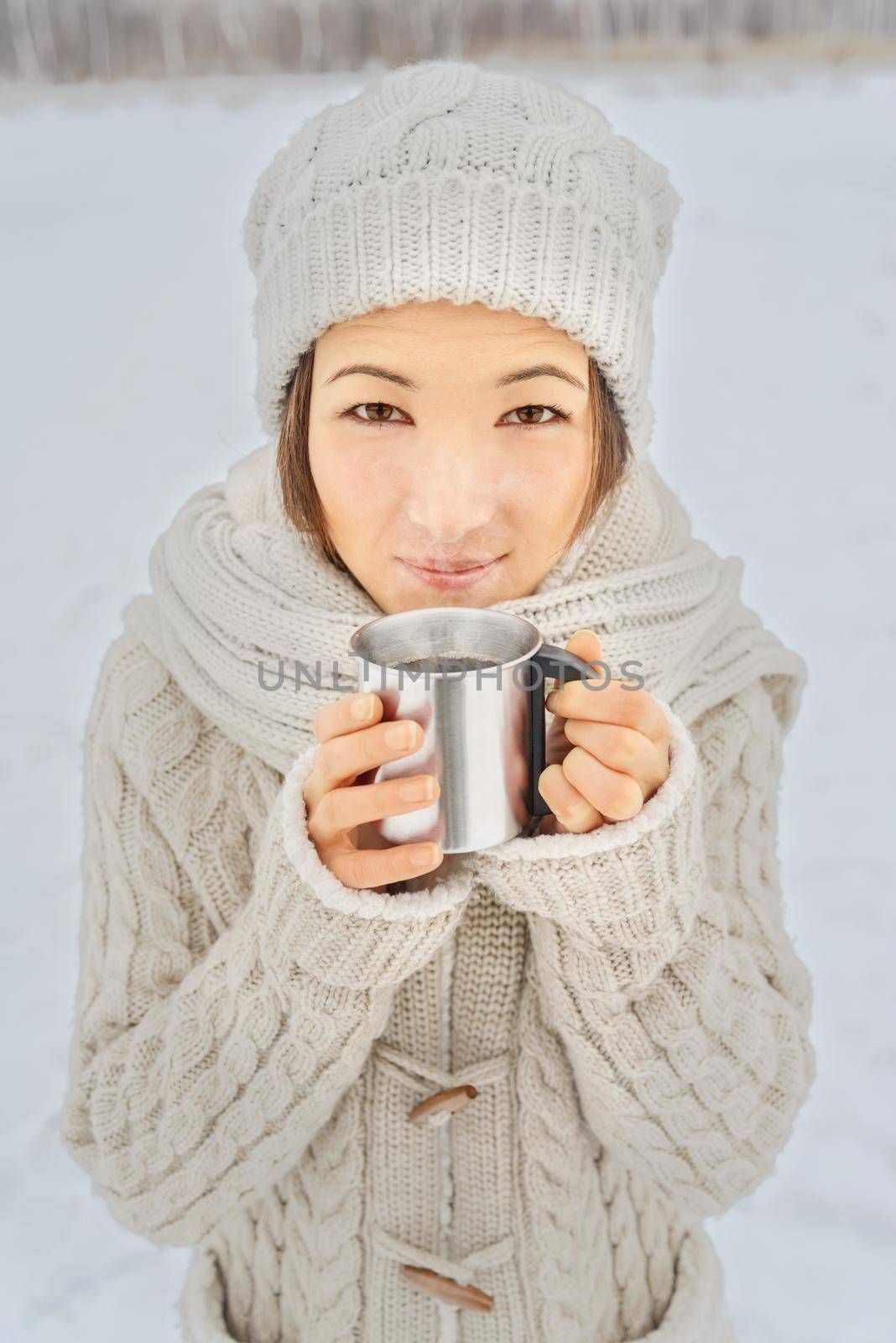 Young happy woman holds a cup of hot coffee in winter outdoors
