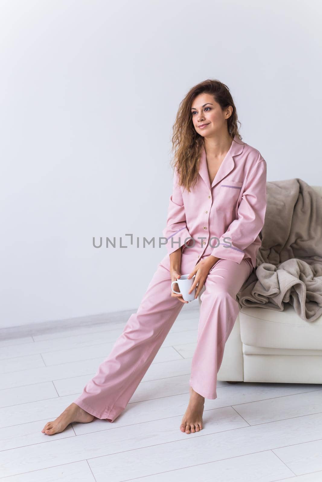 Young attractive woman dressed in beautiful colorful pajama posing as a model in her living room. Comfortable sleepwear, home relaxation and female fashion concept