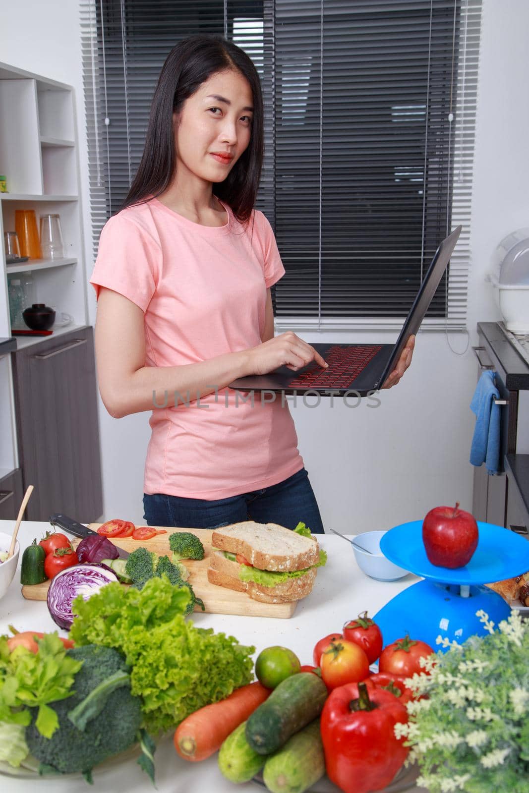 woman cooking and looking with laptop in kitchen room by geargodz