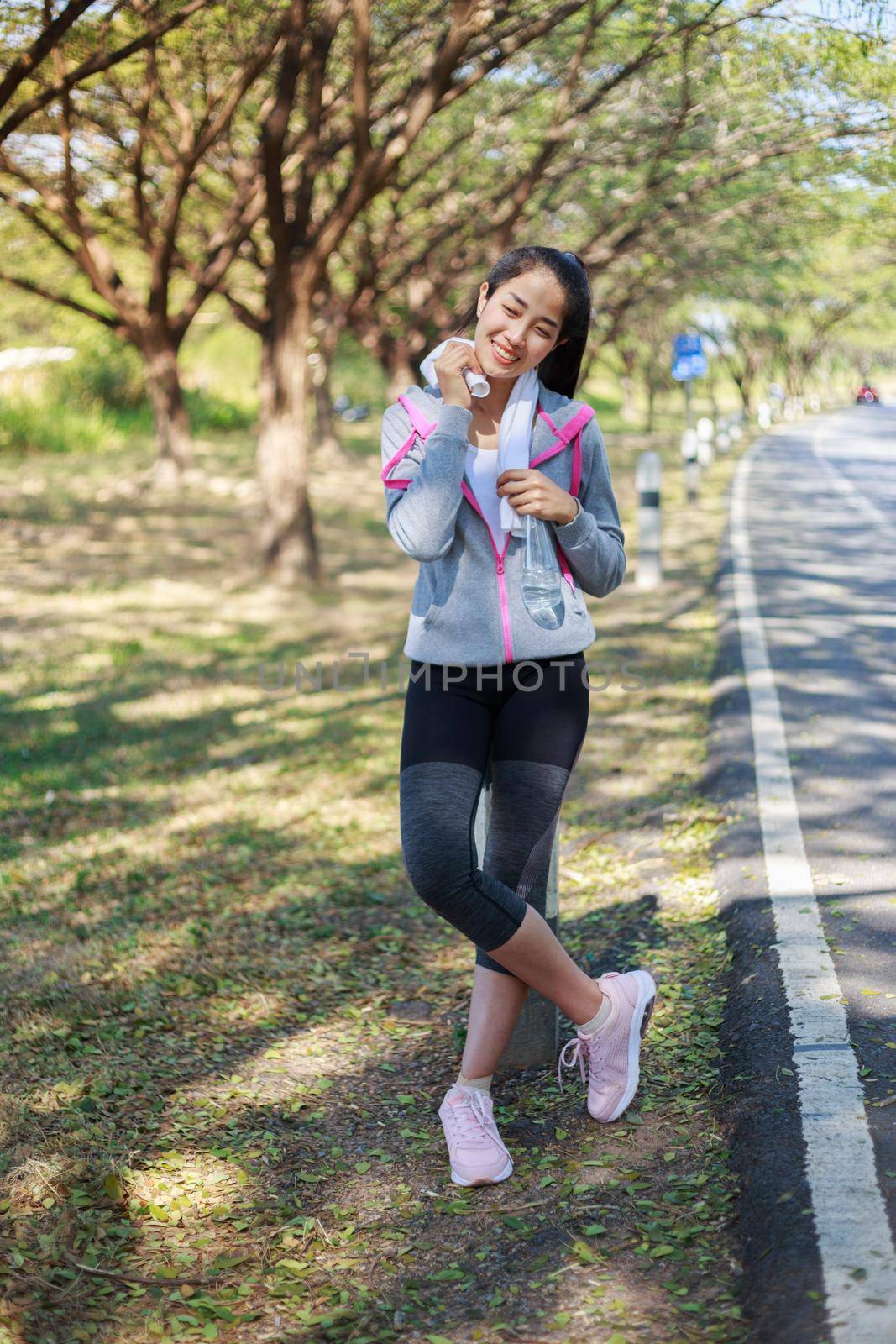 young sporty woman resting and wiping her sweat with a towel after workout sport exercises outdoors at the park