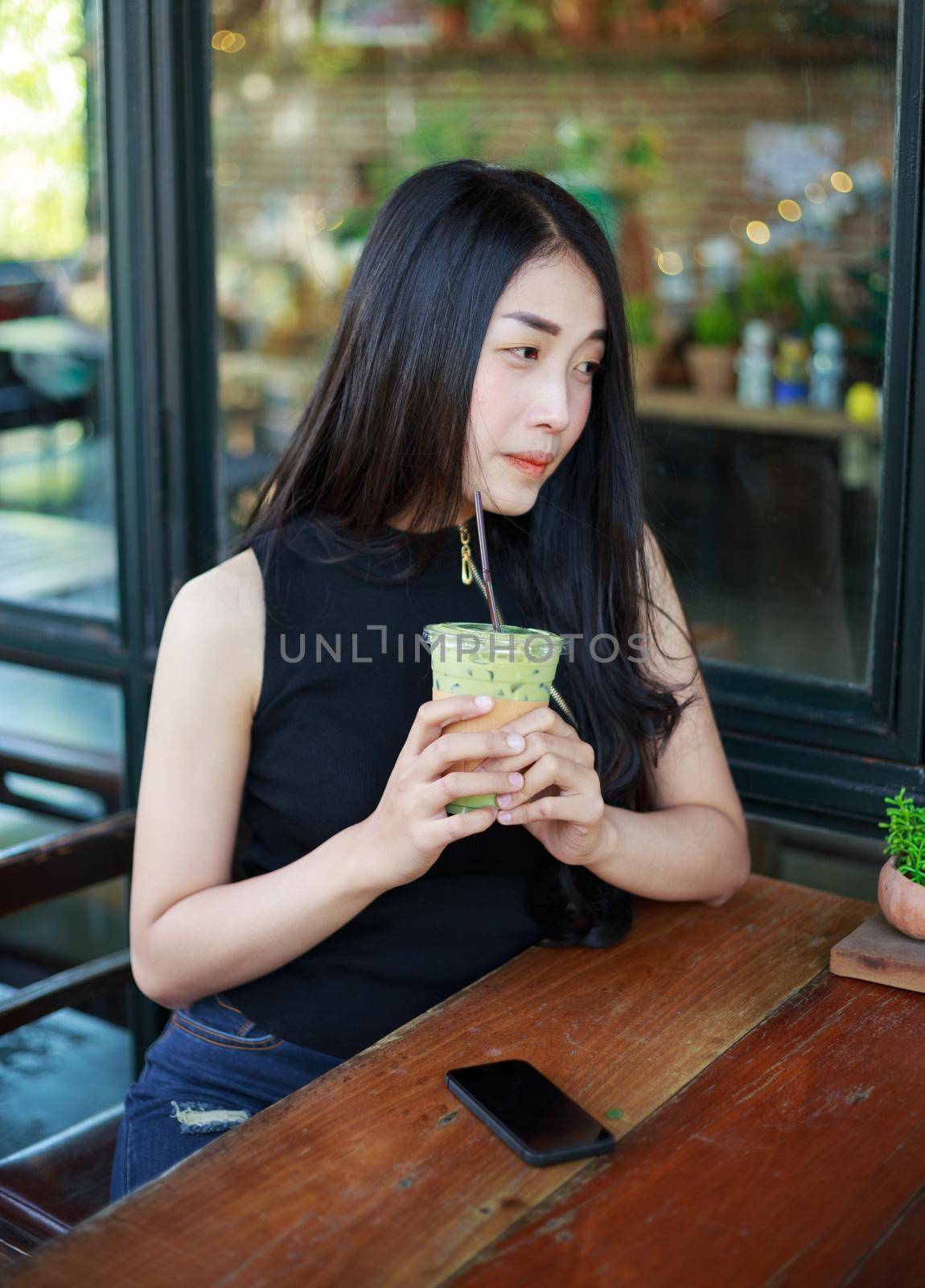 young woman dinking ice green tea latte in the cafe