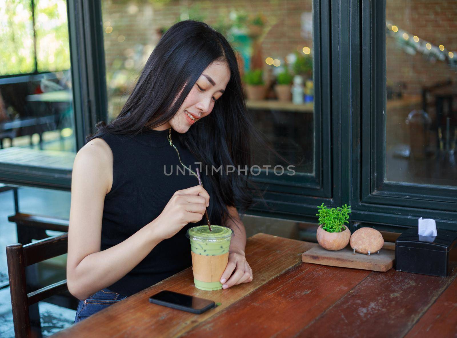 young woman dinking ice green tea latte in the cafe