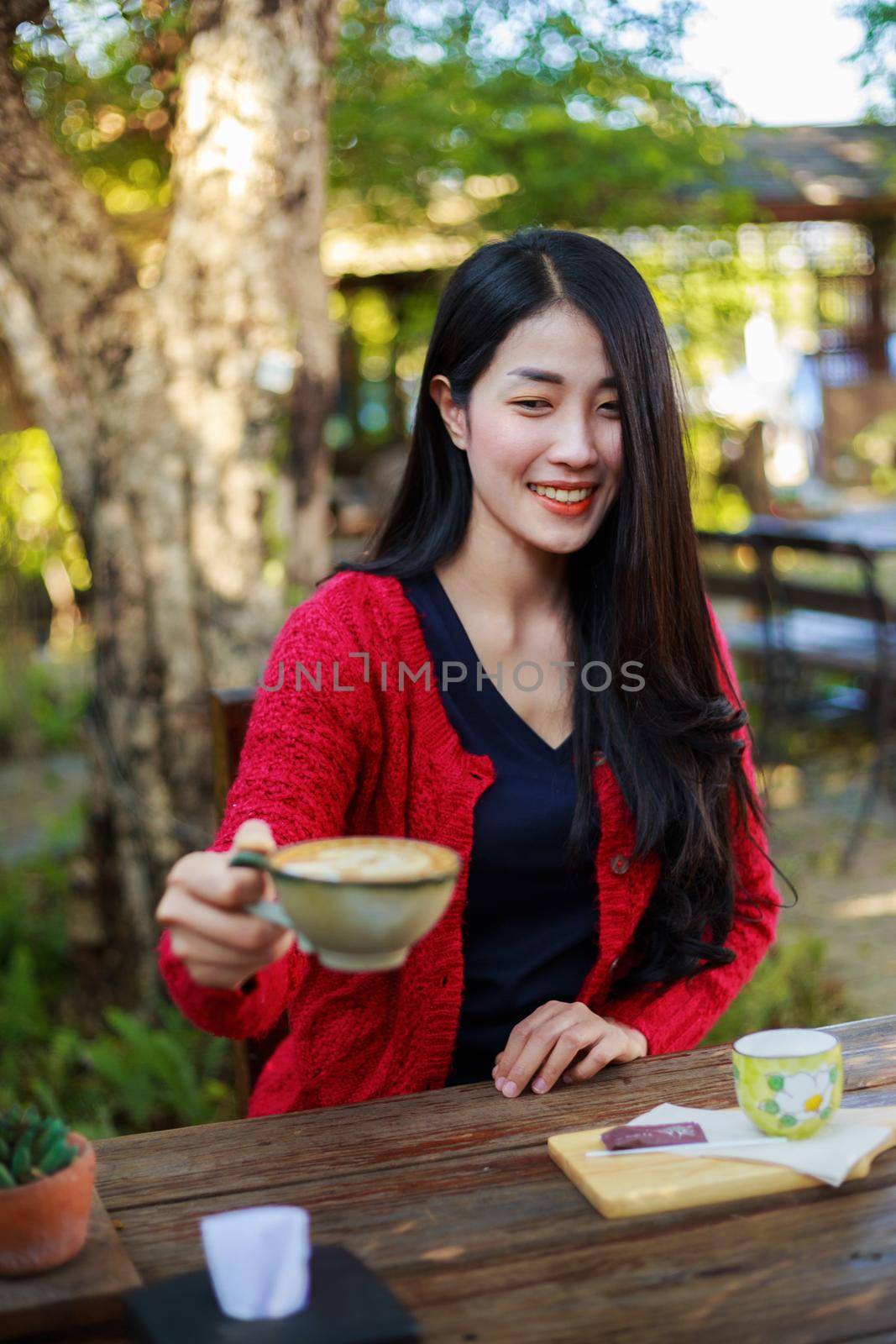 young woman sitting on a table and drinking a cup of coffe in the garden