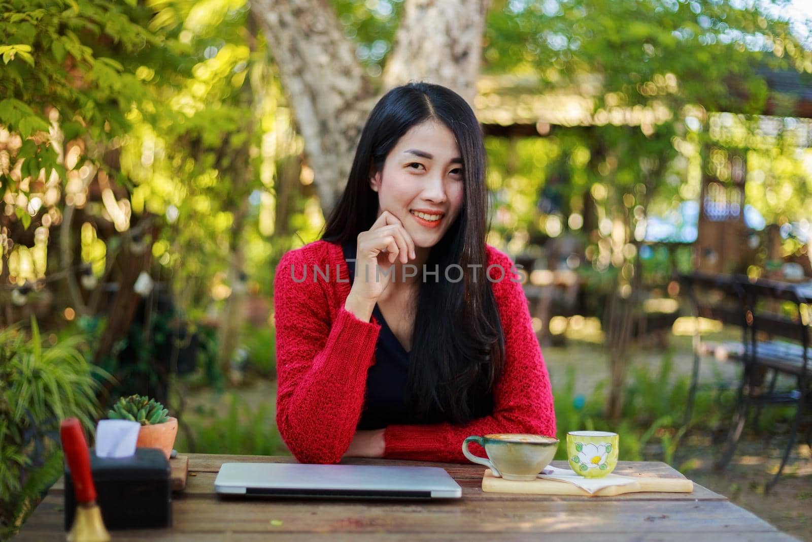 portrait of young woman with laptop and coffee in the garden