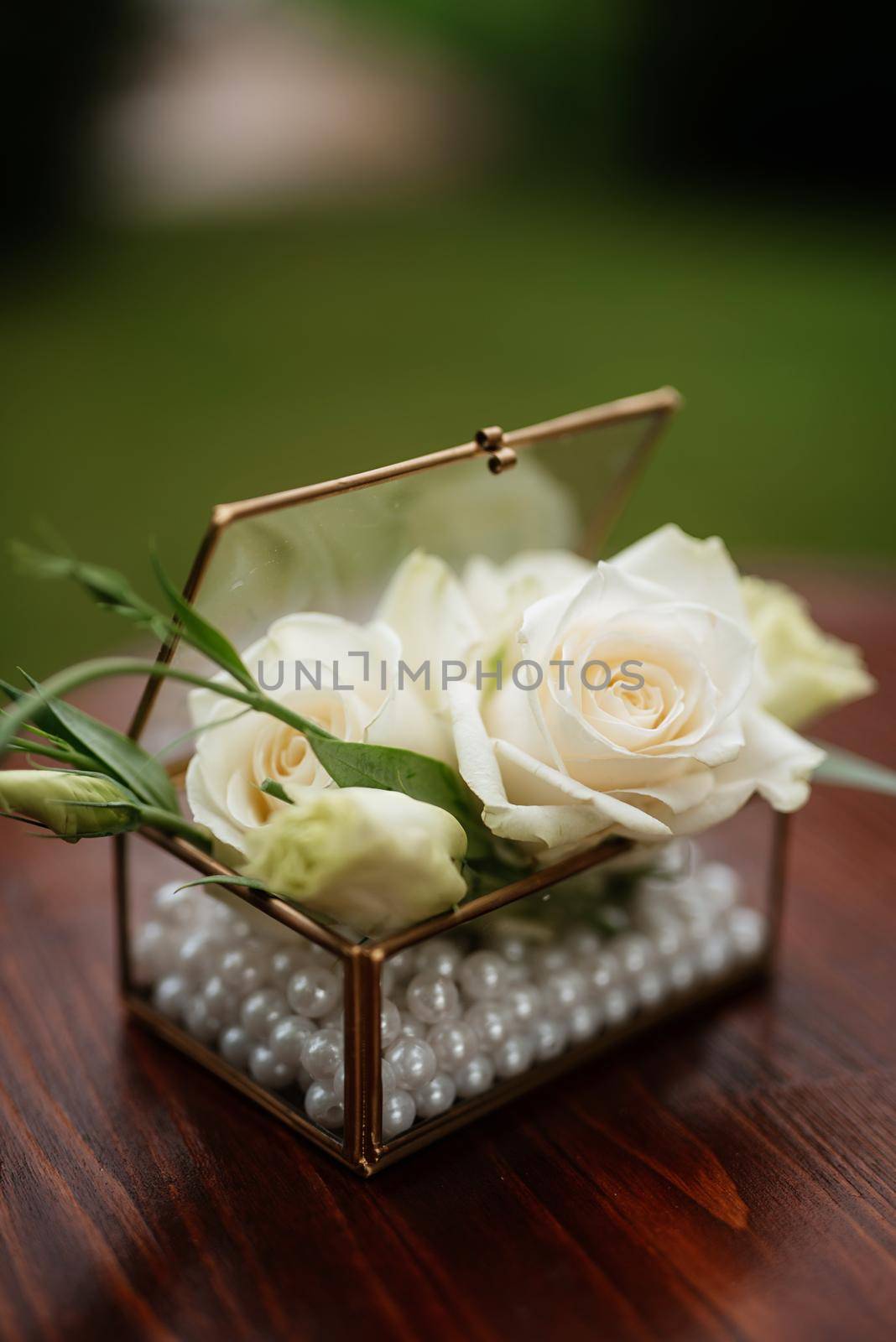 white rose buds in a glass box for wedding rings