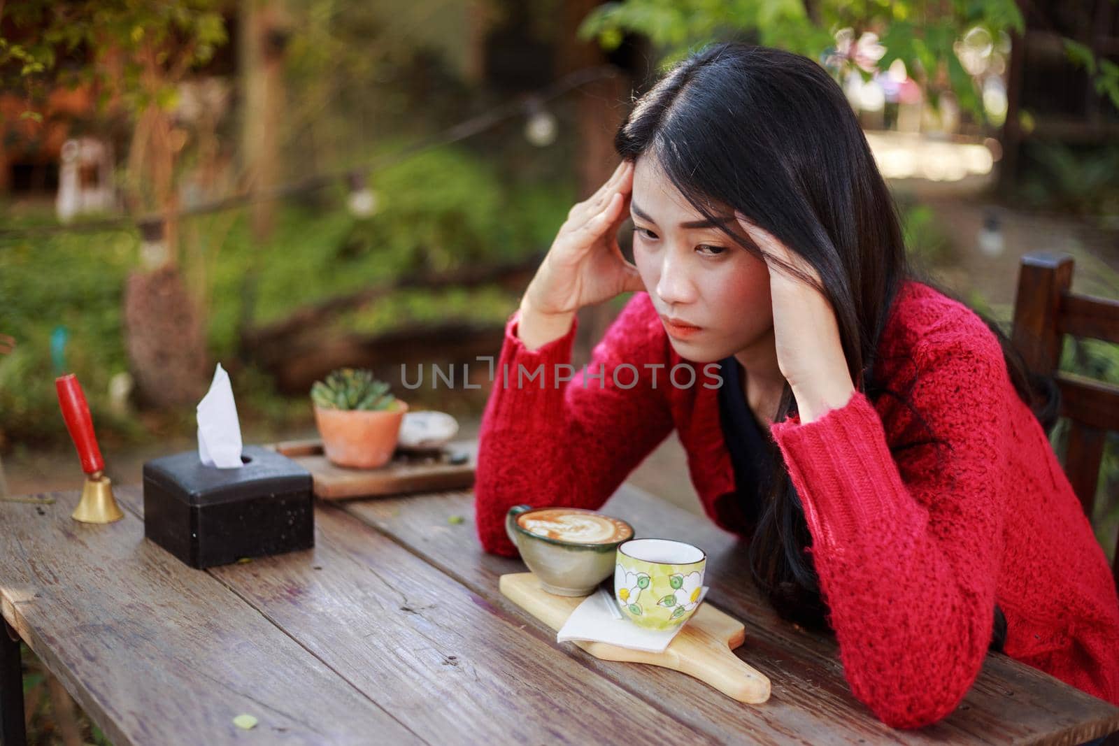 worried young woman with a cup of coffee in the garden