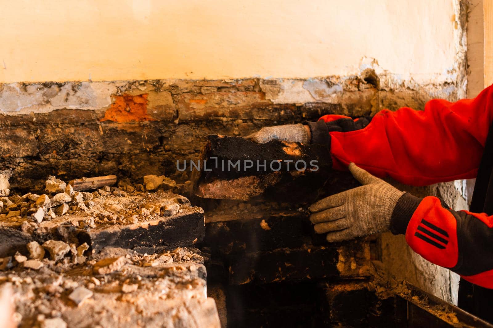Man destroys an old brick stove, black brick in soot, dismantling the old kitchen surface. new