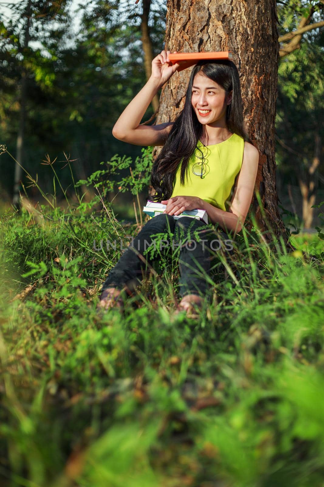 woman sitting and holding a book in the park by geargodz