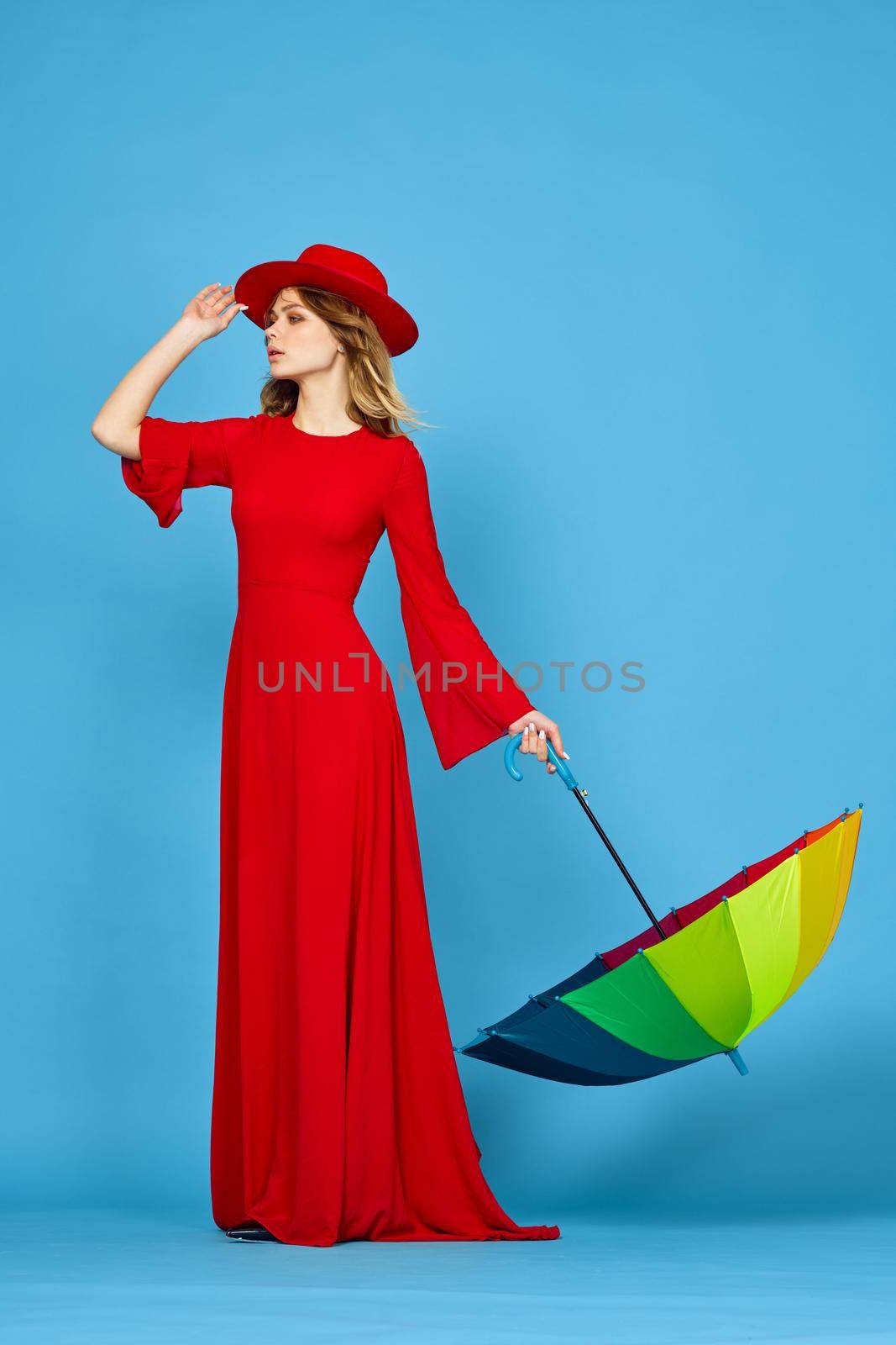 woman in red dress multicolored umbrella blue background. High quality photo