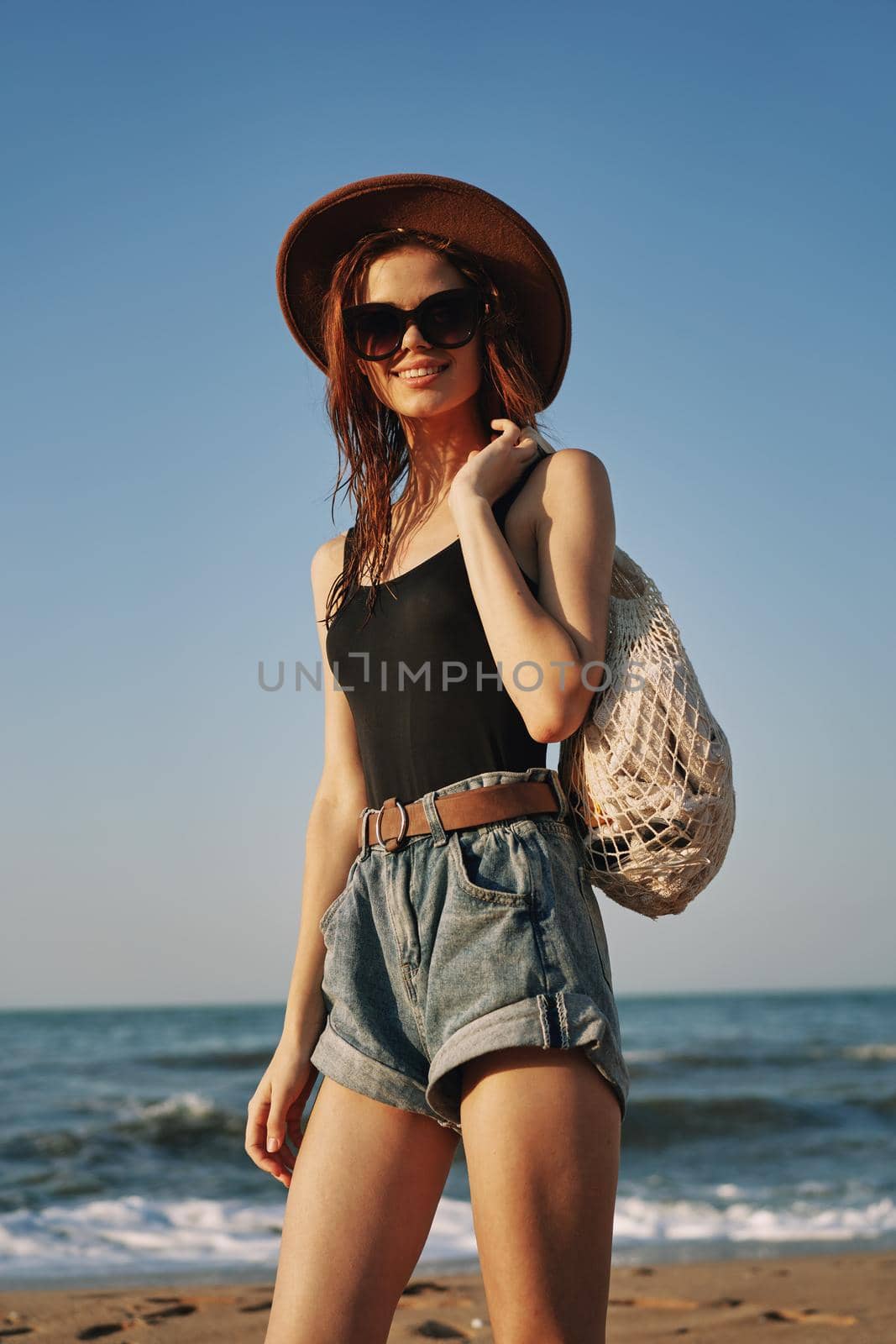 cheerful woman in a hat with sunglasses walking with a bag. High quality photo