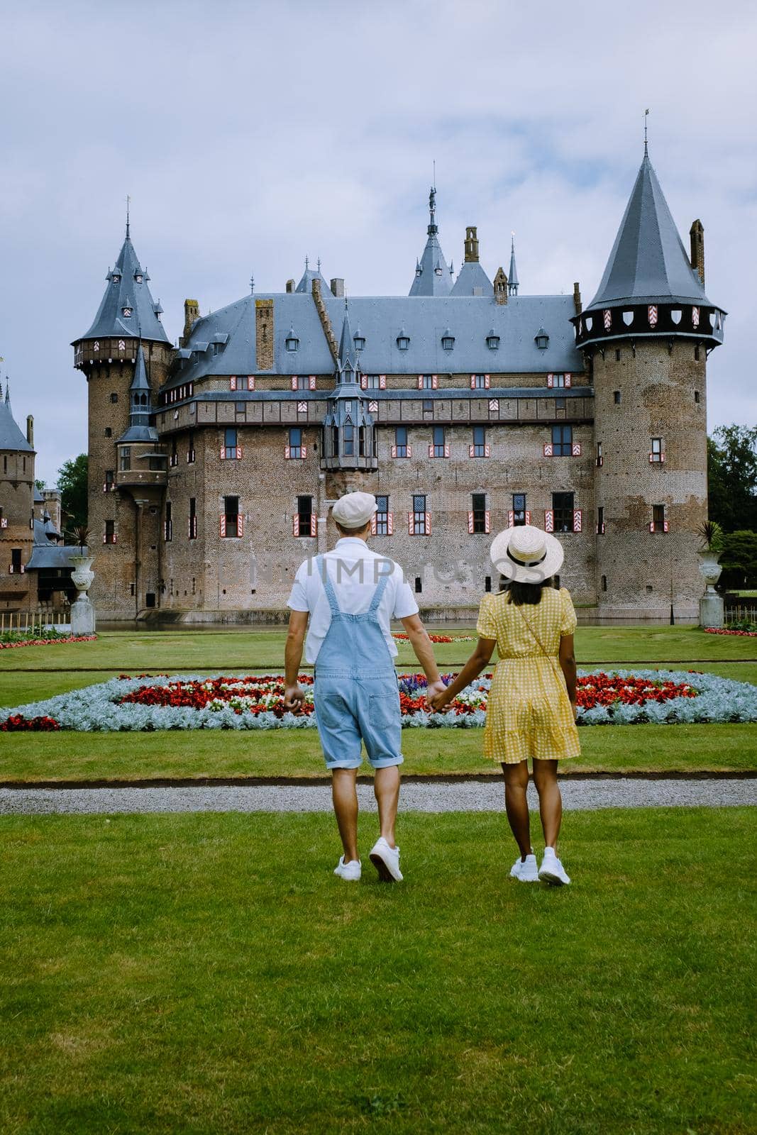 Castle de Haar Utrecht, couple men and woman mid age European and Asian visit De Haar Castle in Dutch Kasteel de Haar is located in Utrecht Netherlands during Spring with flowers in the garden