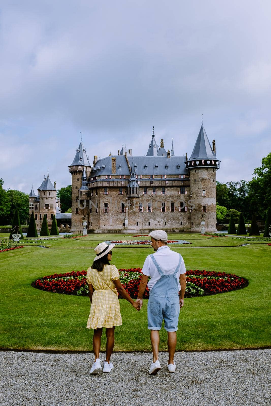 Castle de Haar Utrecht, couple men and woman mid age European and Asian visit De Haar Castle in Dutch Kasteel de Haar is located in Utrecht Netherlands during Spring with flowers in the garden