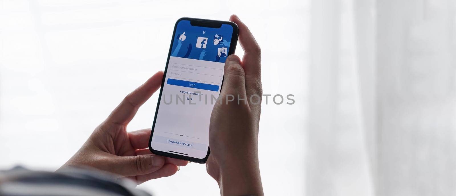 CHIANG MAI ,THAILAND JUL 18 2021 : Woman holding a iPhone X with social Internet service Facebook on the screen..