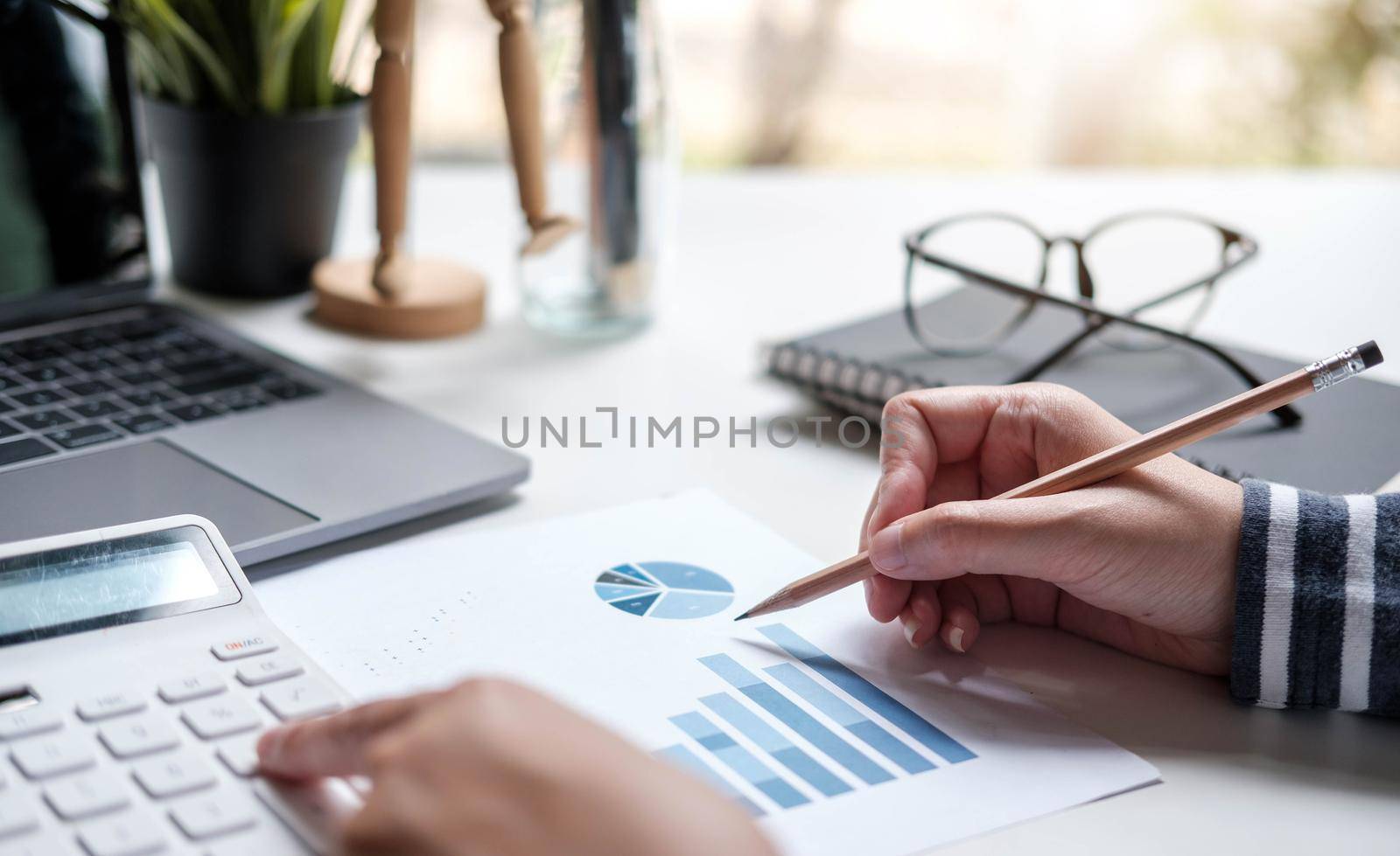 Close up asian business woman using a calculator to calculate the numbers.Business finances and accounting concept by wichayada