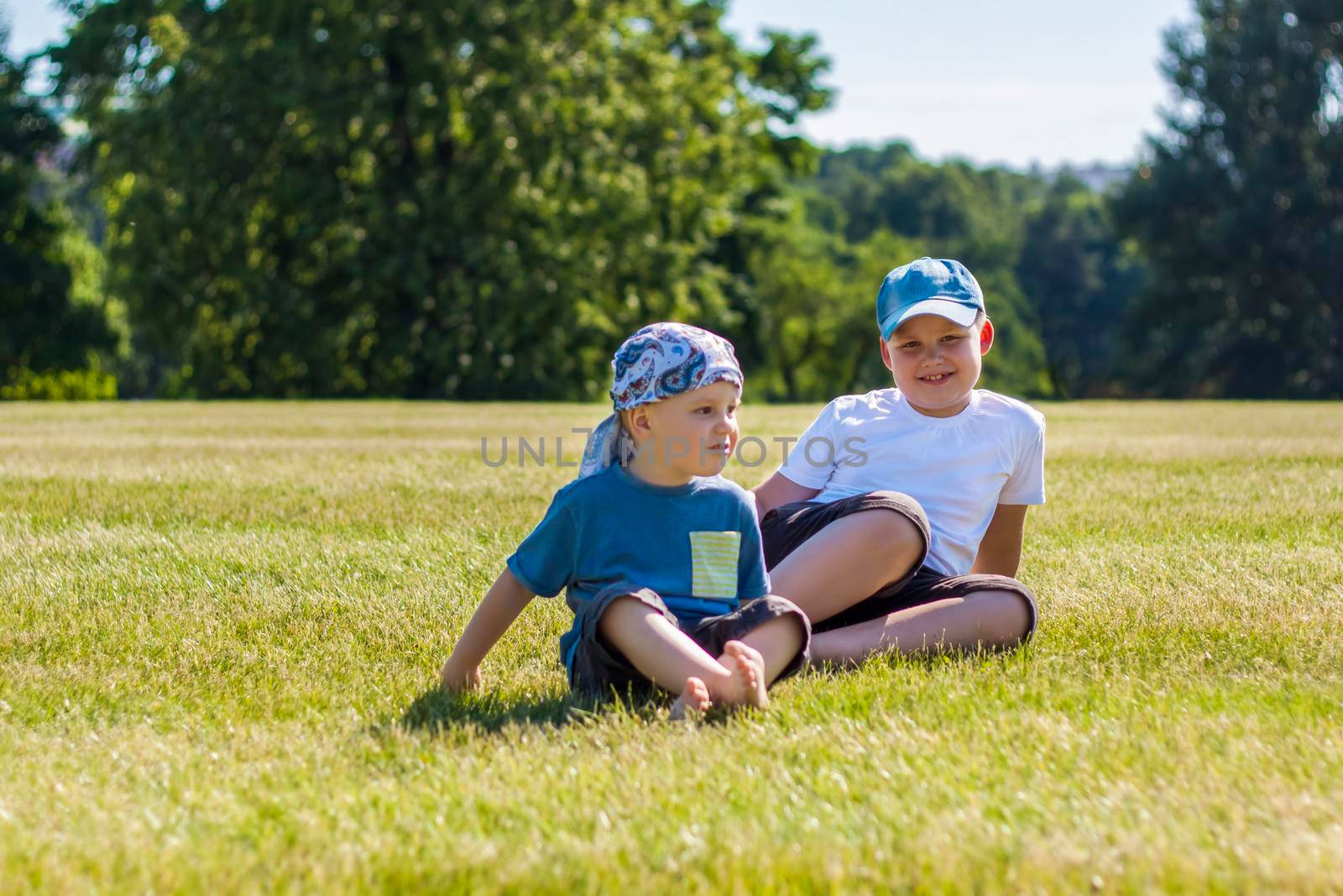 Cheerful children, two brothers, smile with joy. we are happy to walk and play on the lawn in warm sunny weather in the park. the emotions of children on the face. Happiness 