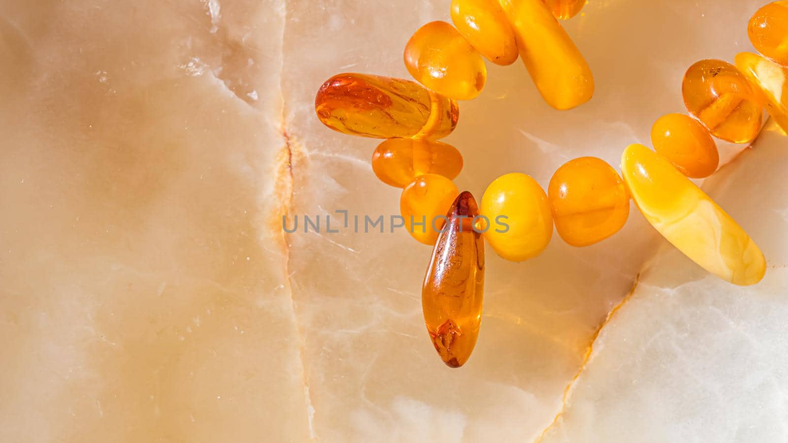 Solar beads of fiery amber on onyx marble background. Natural stone backdrop.