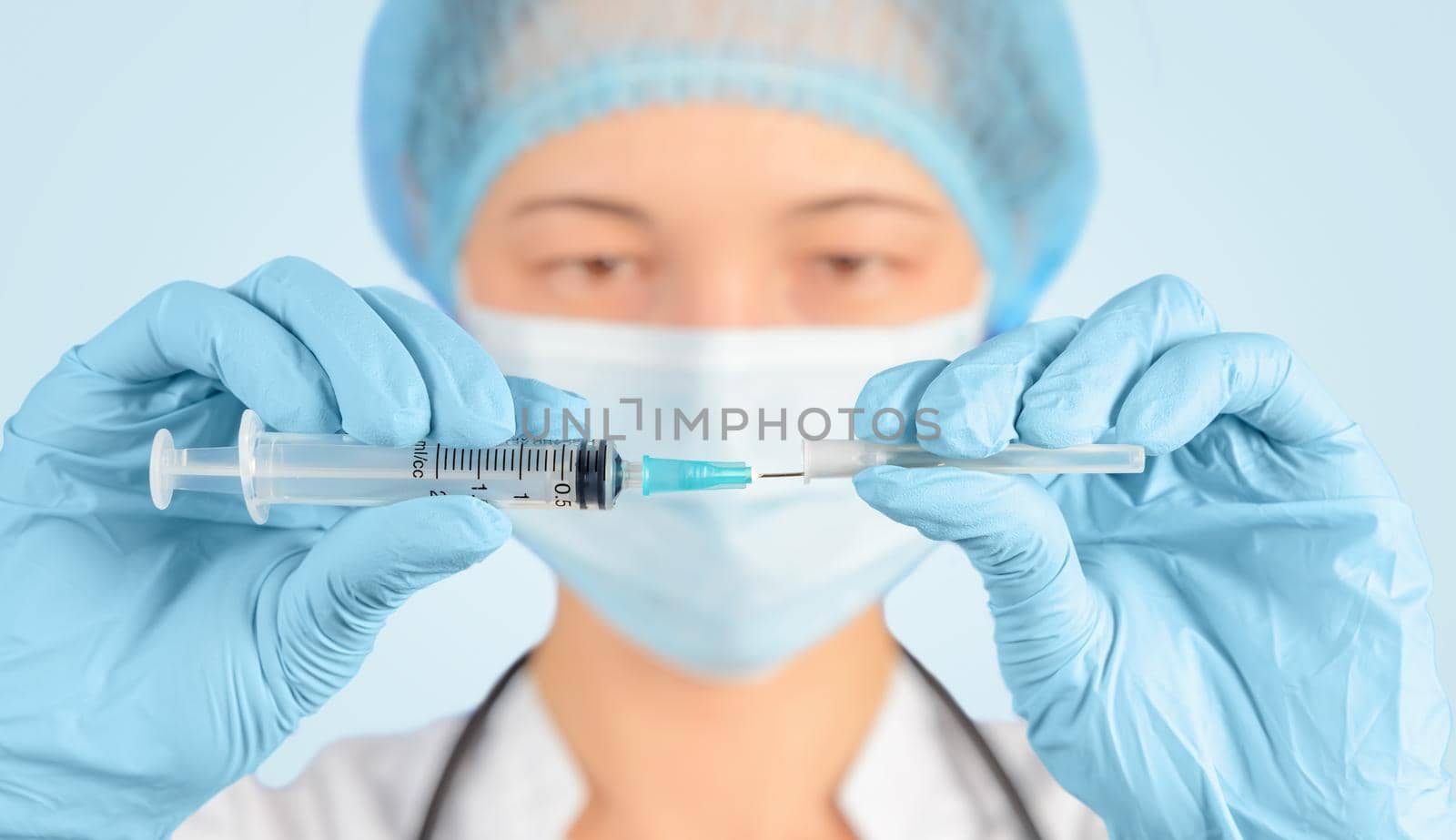 Nurse in a cap and gloves is opening syringe