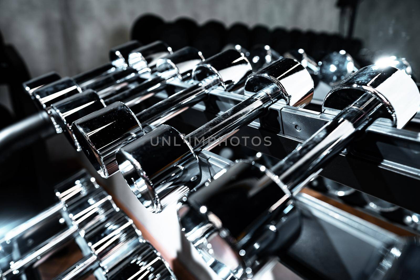 Rows of metal dumbbells on rack for bodybuilding in a gym