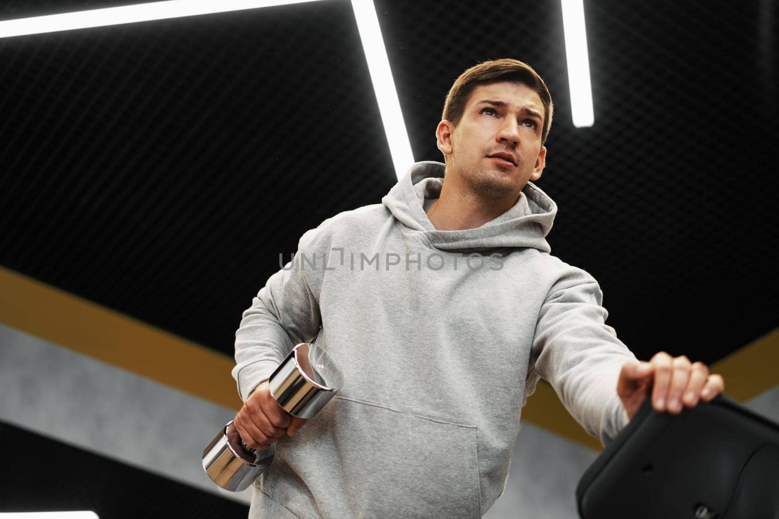 Determined handsome young male working out in gym with dumbbells, close up