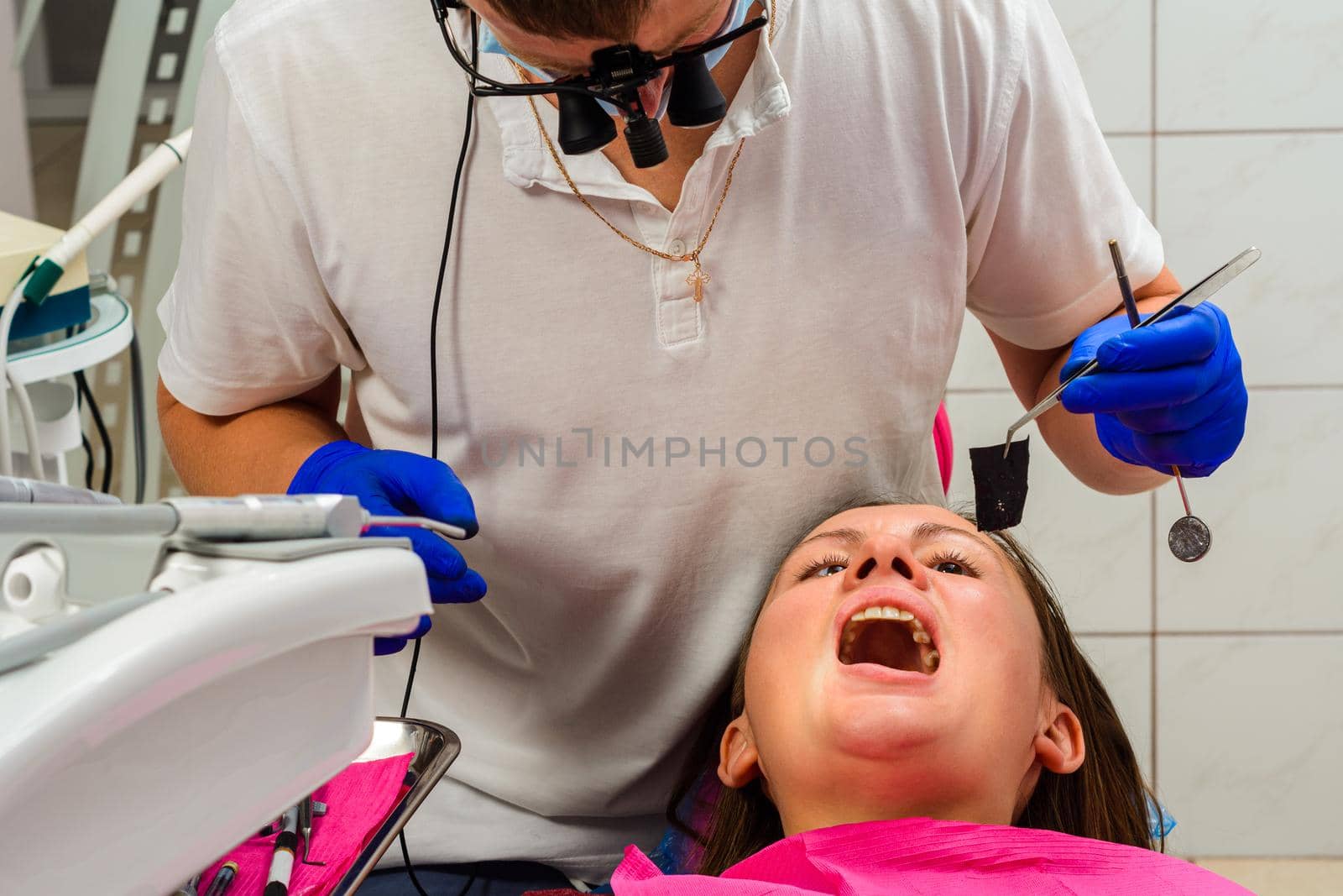 After filling, the dentist removes the excess material from the tooth with a copying tracing paper. by Niko_Cingaryuk