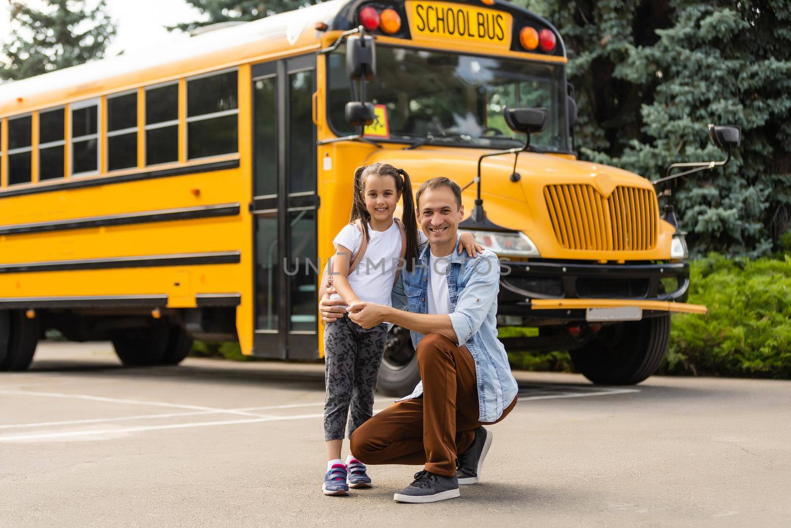 Girl with father going back to school near the school bus