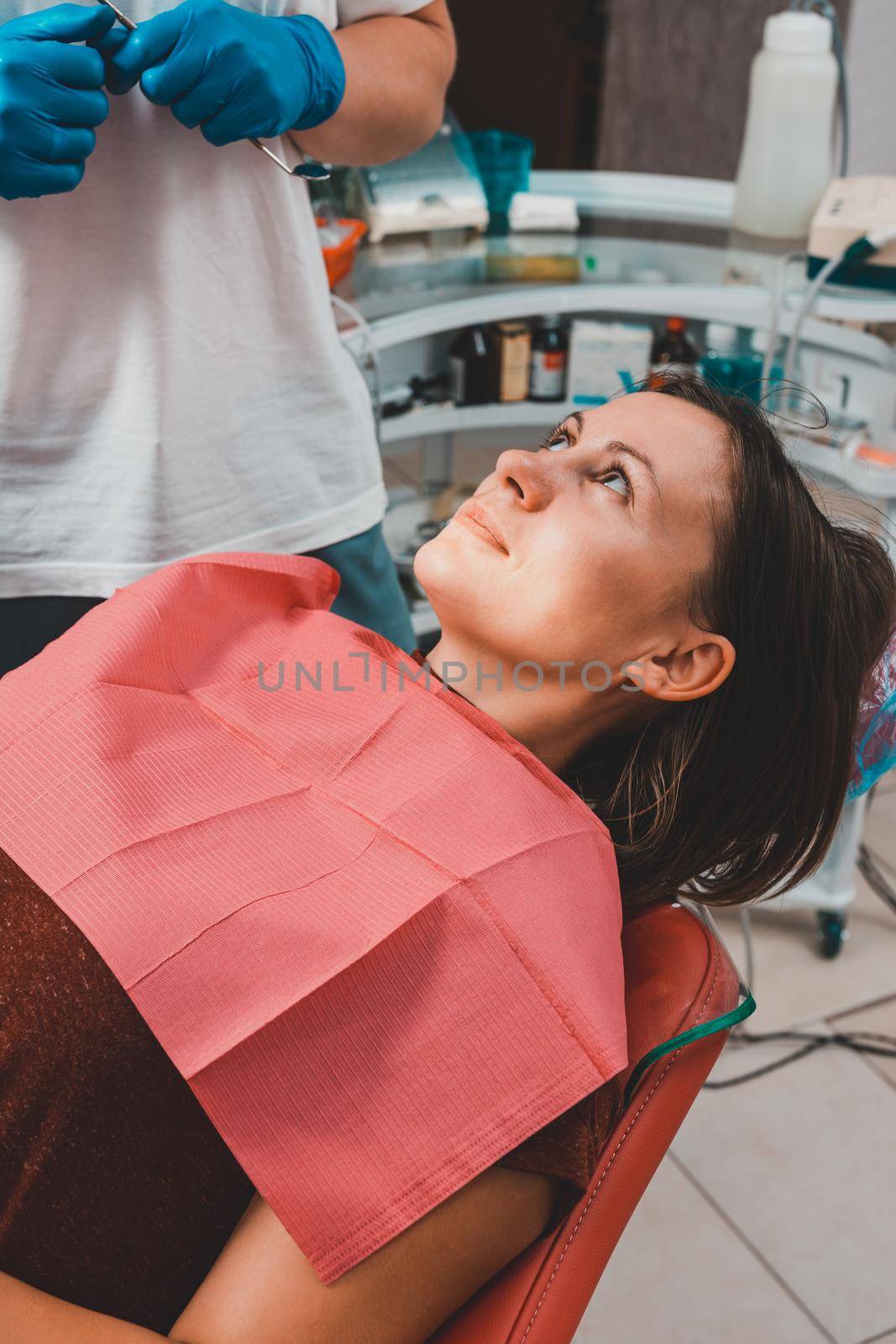 A young woman is preparing for a dental examination by a dentist, the patient is sitting in a dental chair. Happy patient in a dental chair 2021.