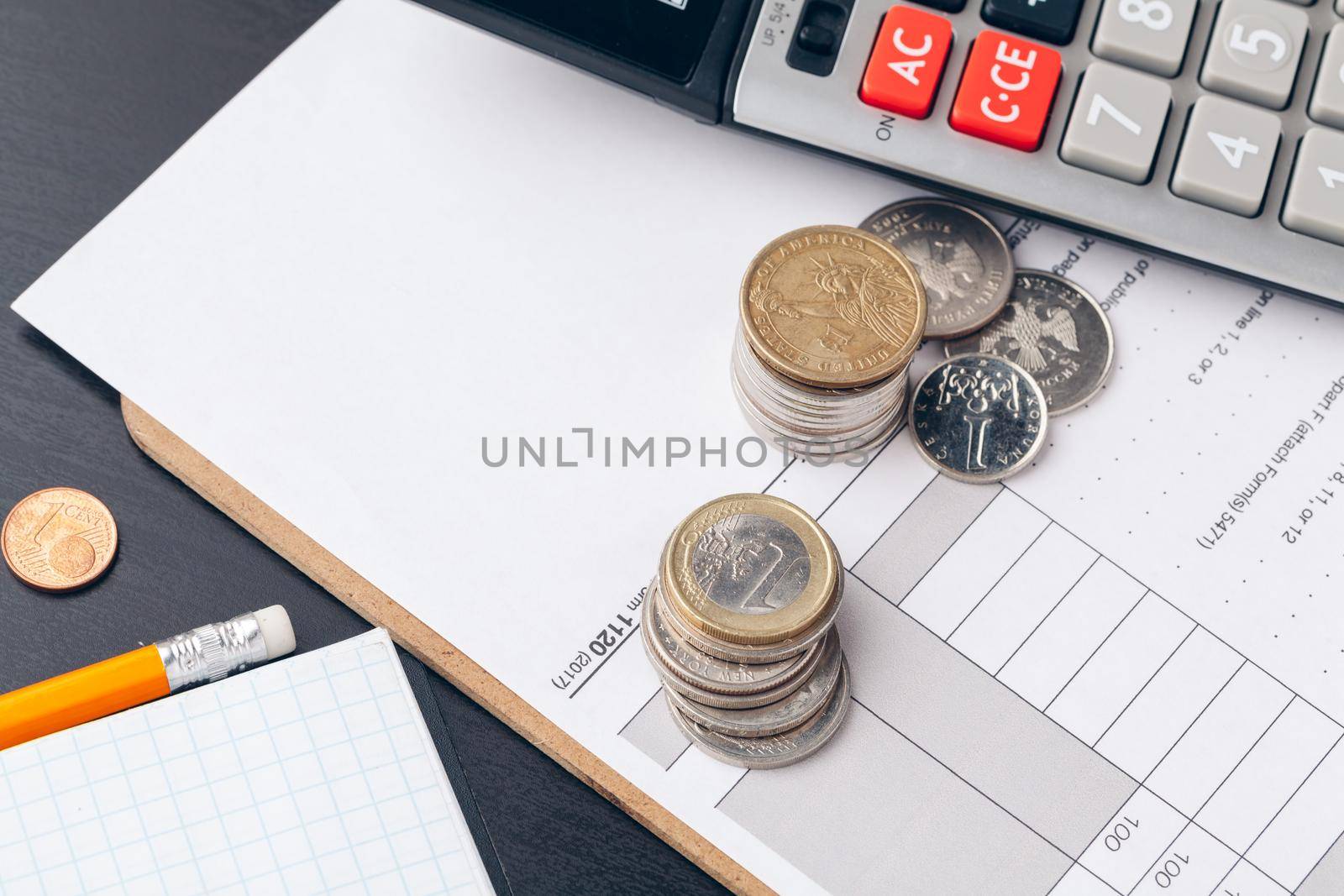 pile of money coins with graph paper on wood table, concept in account, finance and growth of business