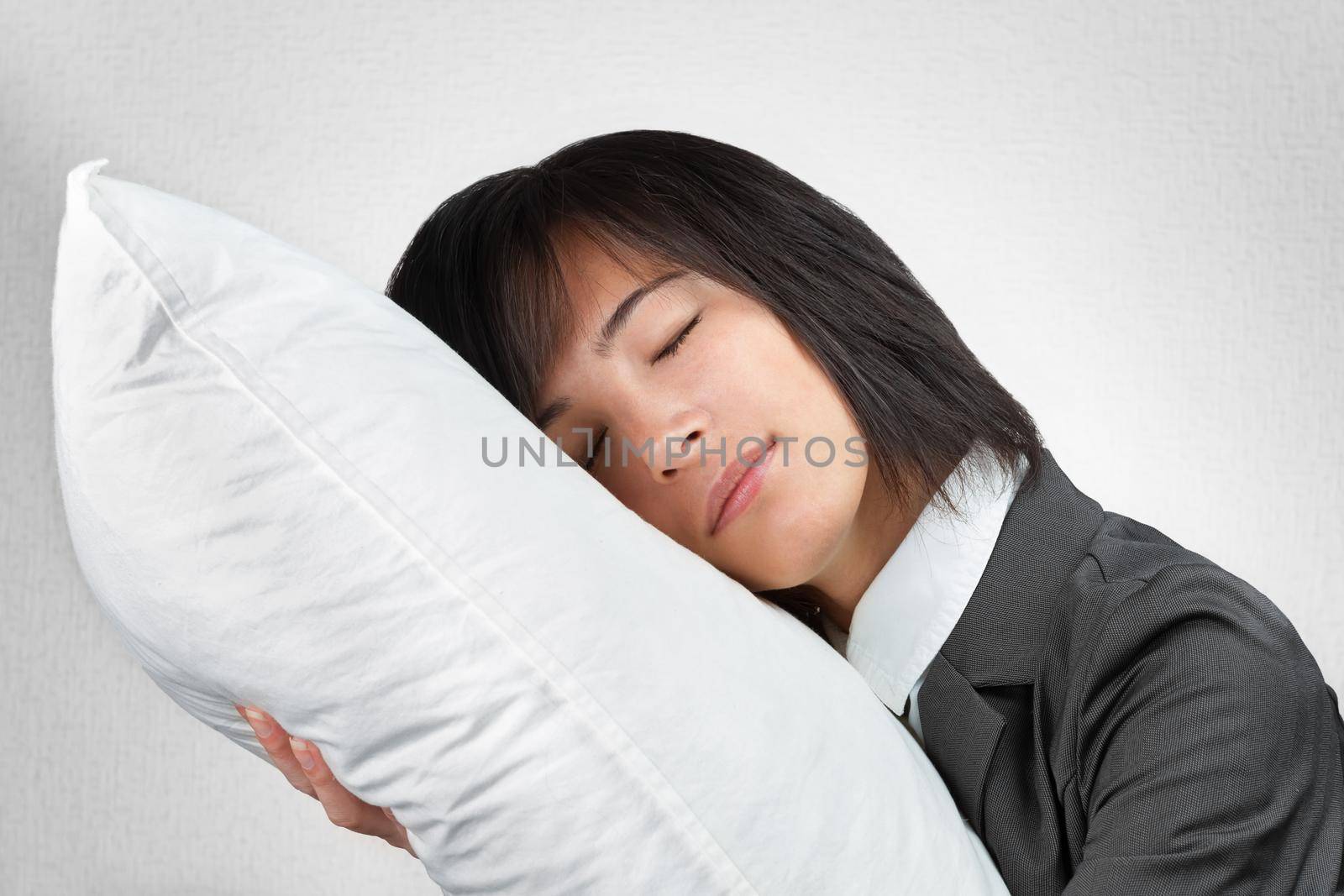 Business woman in a suit hugging a pillow with closed eyes