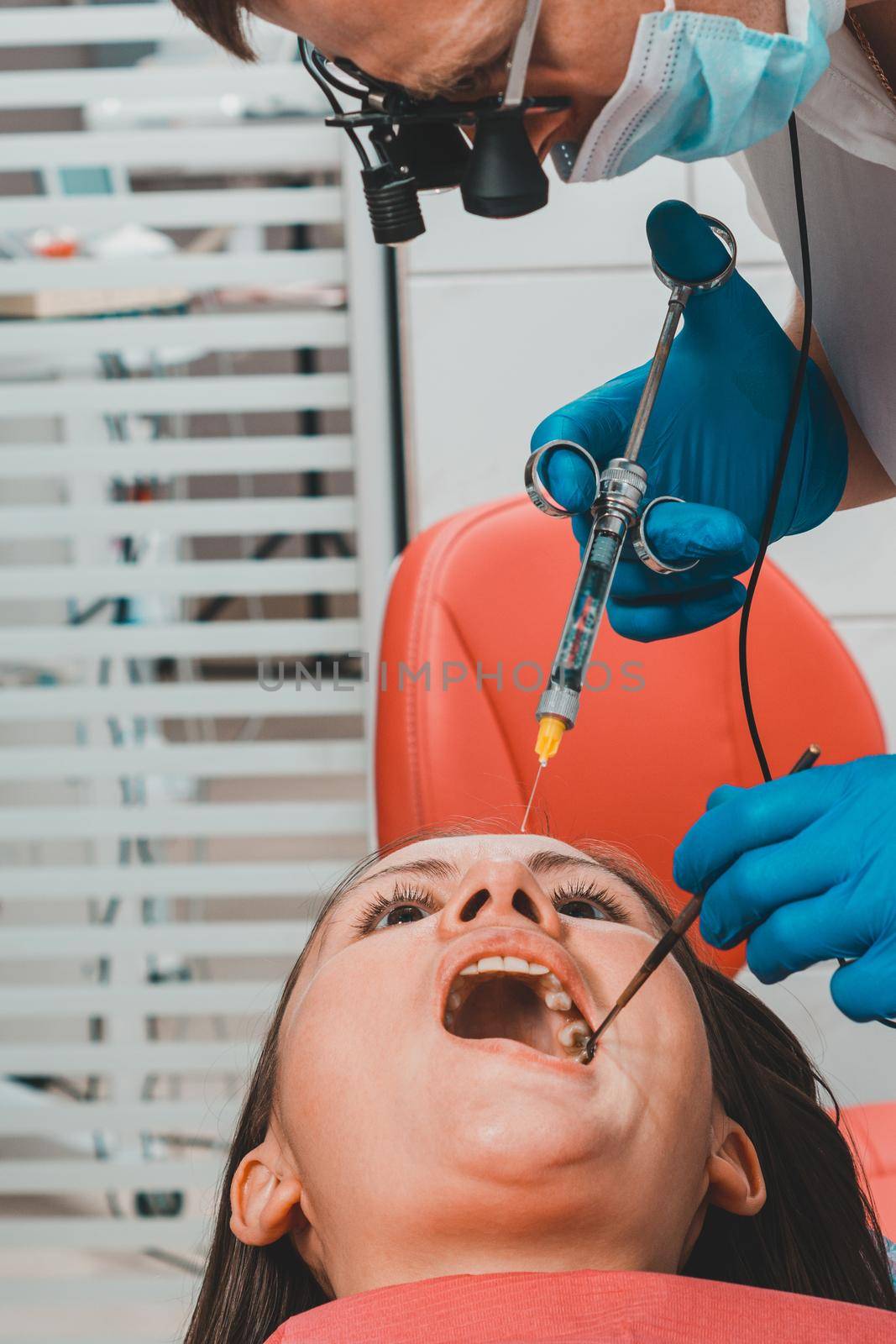 The dentist with the help of a carpule syringe injects anesthesia into the patient's gums, local anesthesia. by Niko_Cingaryuk