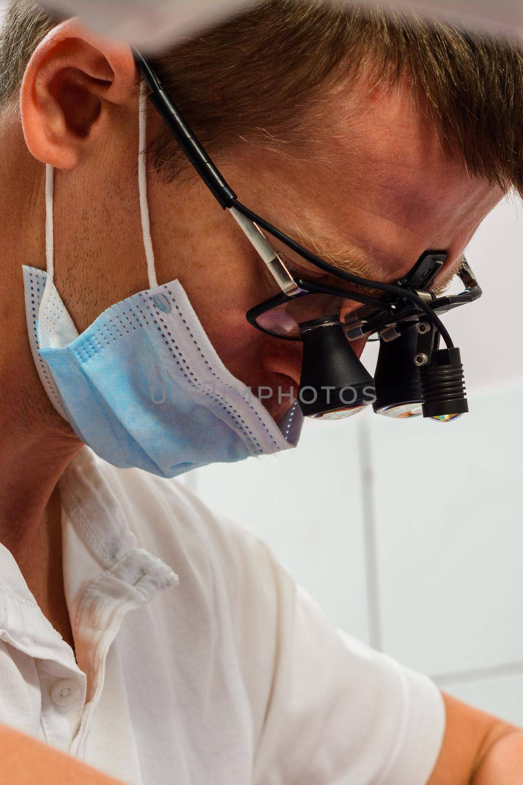 Dentist in binoculars, use of binoculars in dental treatment, dentist in the office, magnifying glass for binoculars. by Niko_Cingaryuk