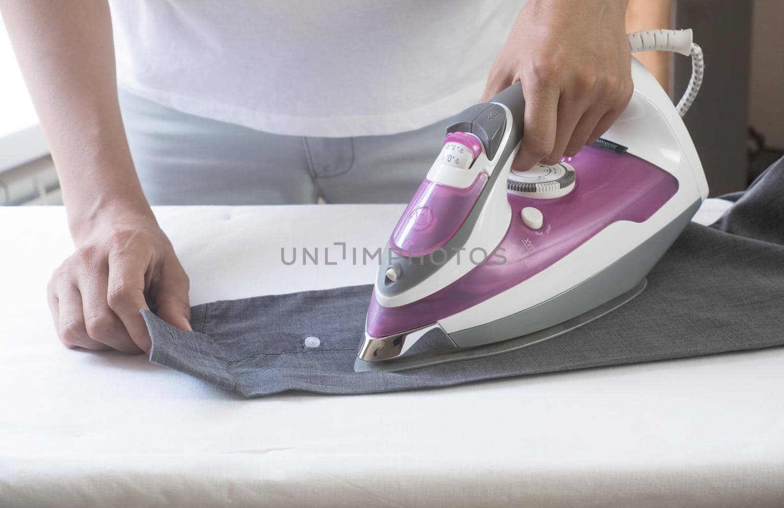 closeup hand of woman ironing clothes blue skirt on ironing board. by Ekaterina34