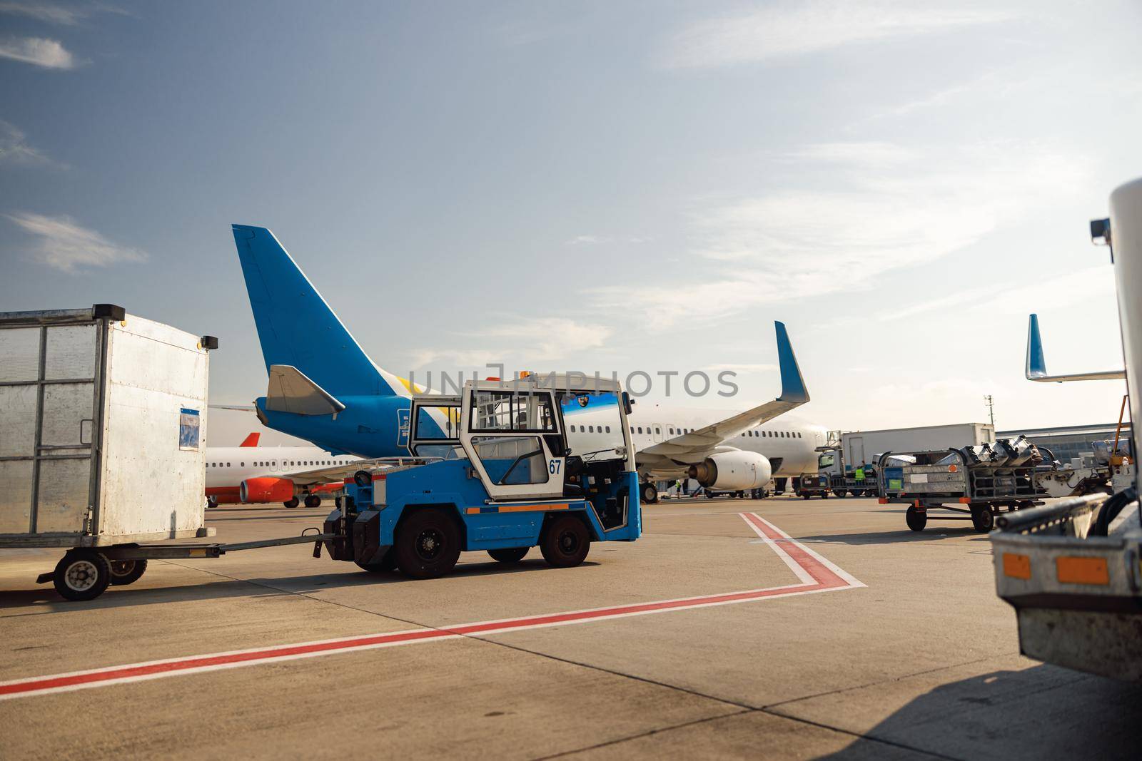 Airfield tractor near big modern airplane. Preparation of aircraft in airport hub on a daytime by Yaroslav_astakhov