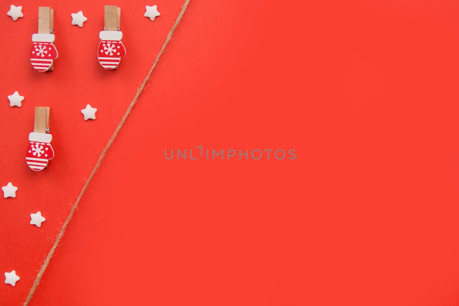 Christmas decorations decorative background. Decorative pins in the form of red gloves on a red background. Top view, minimalism, flat lay. Space for text.