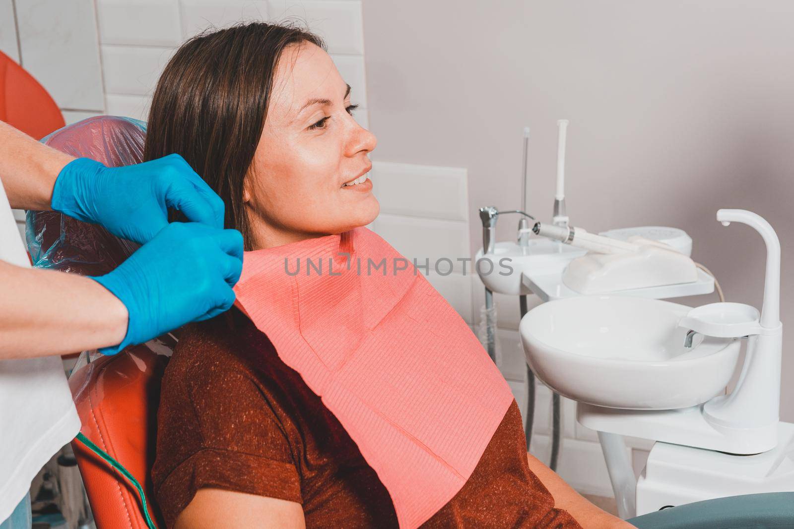 A young woman is preparing for a dental examination by a dentist, the patient is sitting in a dental chair. Happy patient in a dental chair 2020