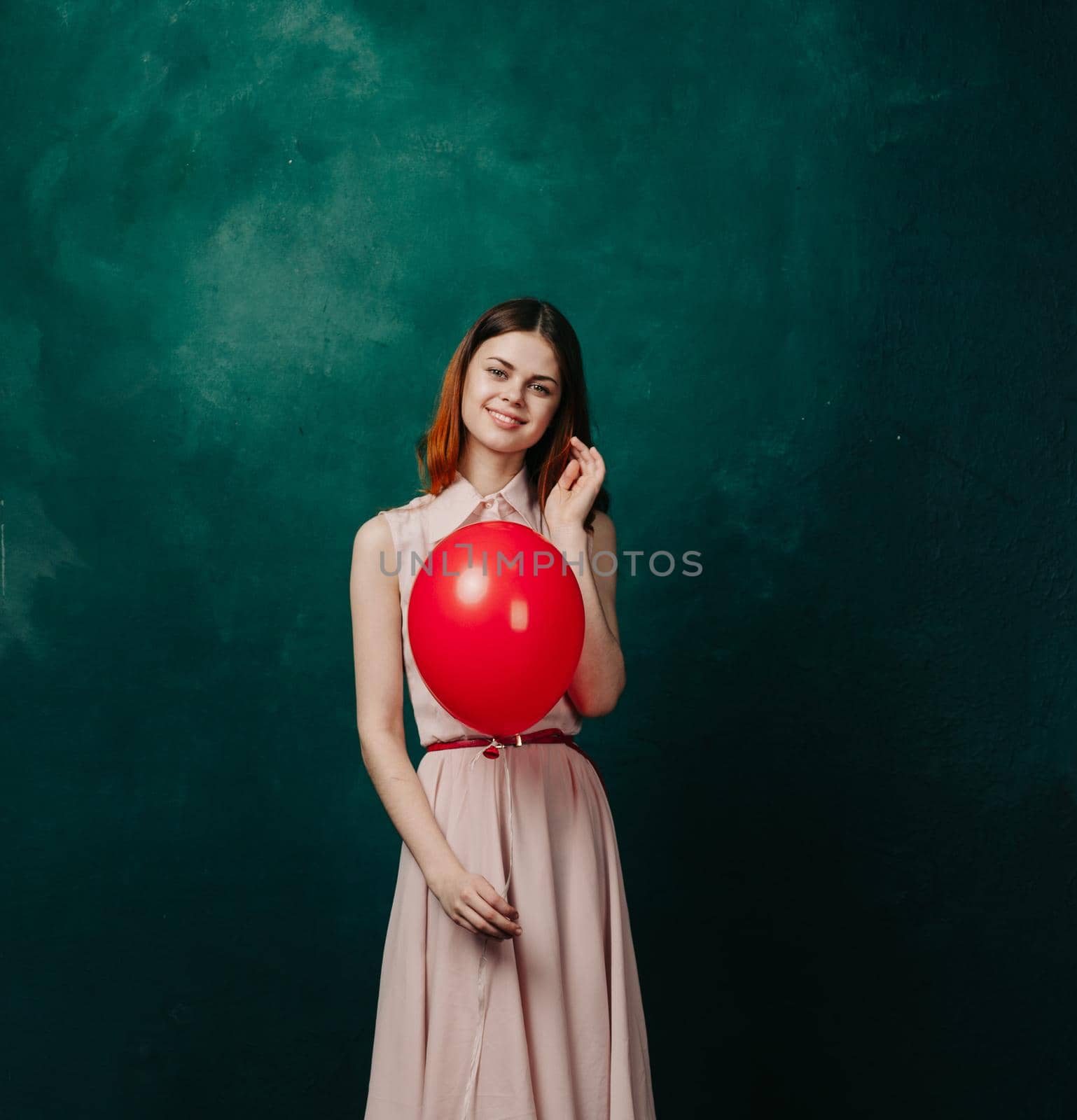 woman with red balloon on green background holiday fun. High quality photo
