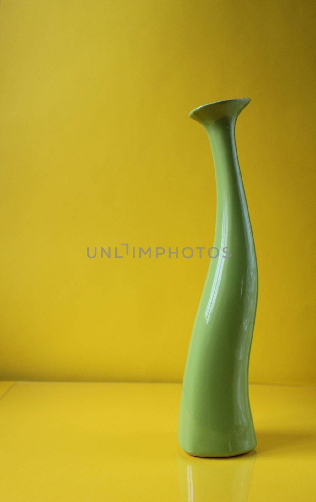 Green asymetric vase on trend color Illuminatiited yellow background with copyspace place for text.
