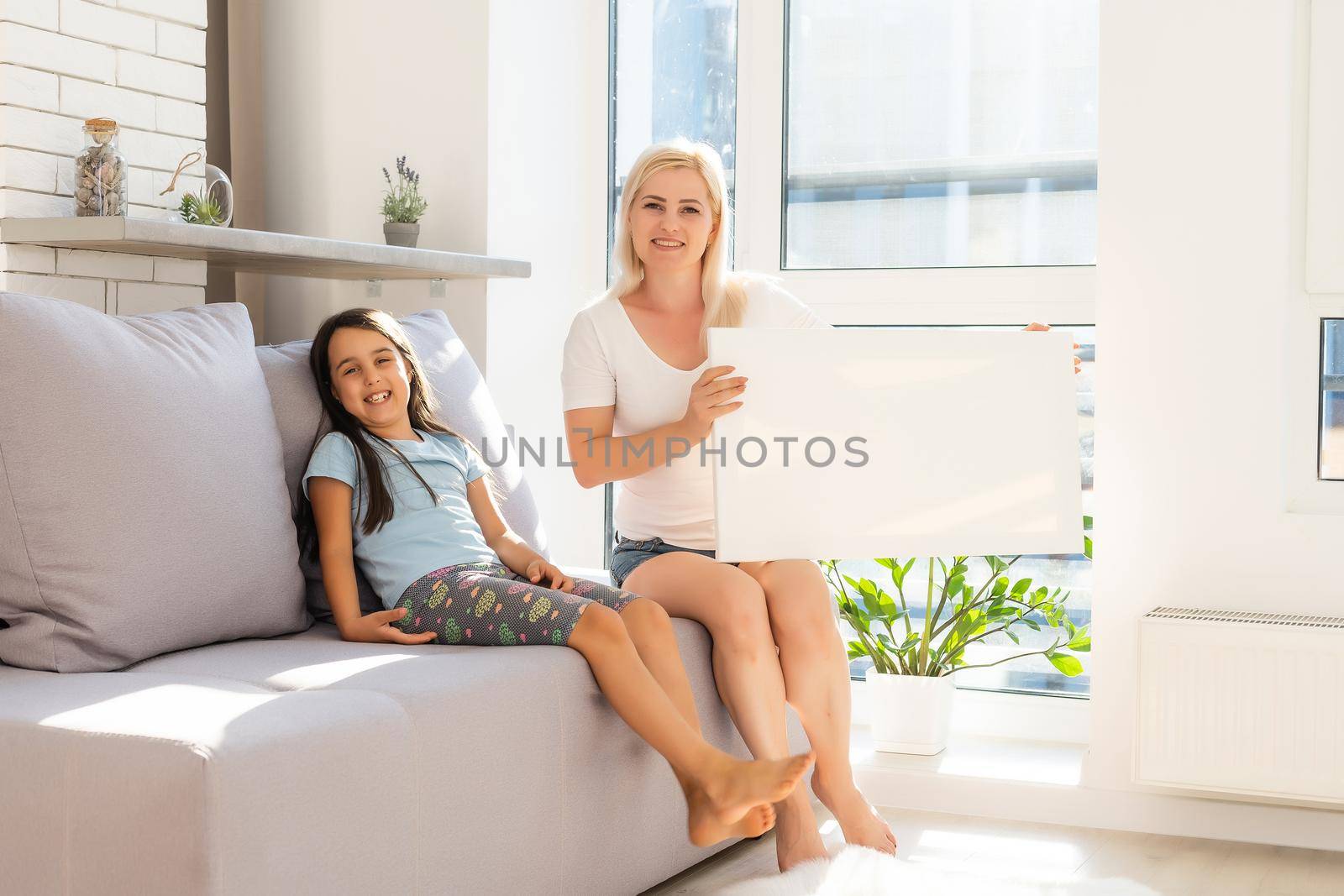 mother and daughter hold photo canvas at home by Andelov13
