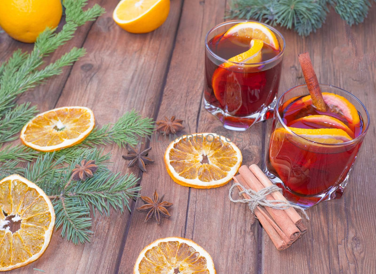 Christmas mulled wine on a wooden background with spices and spruce branches and dried orange