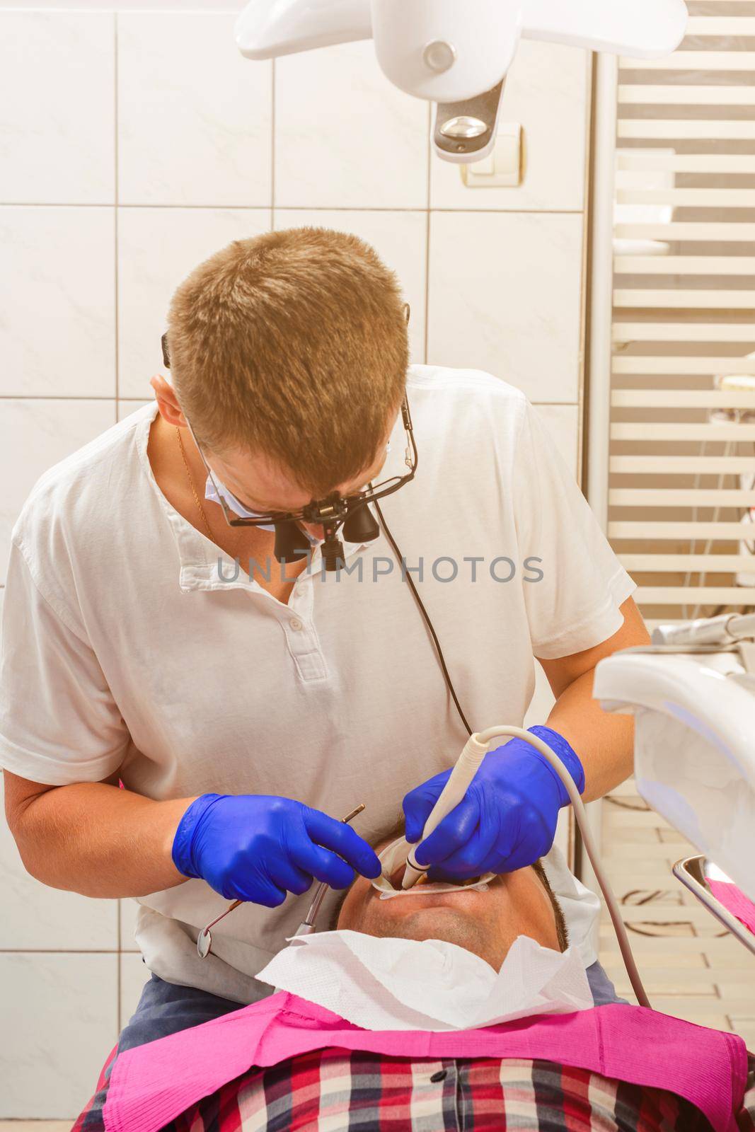 Dentist in the clinic,tartar removal procedure,the dentist in binoculars removes tartar in the patient's mouth.2020