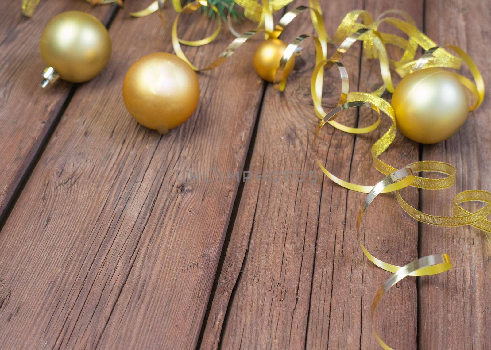 Christmas composition of yellow Christmas balls, fir branches, and a gold ribbon on a brown wooden background. by Ekaterina34