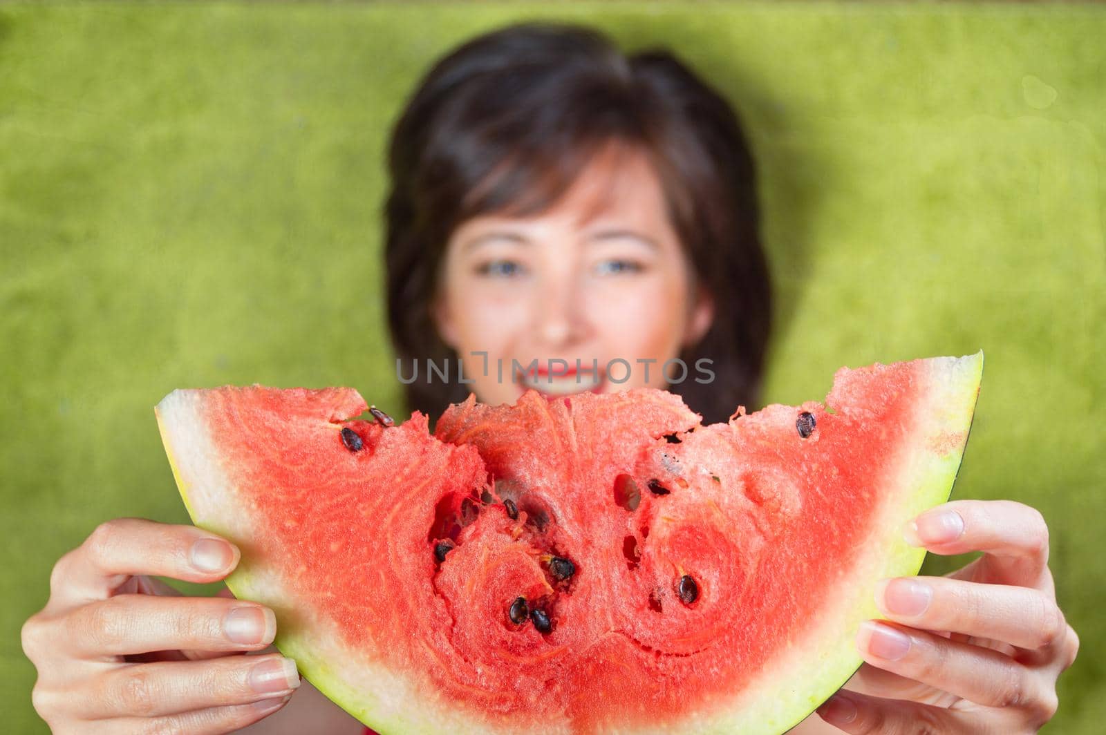 Young woman gives a piece of watermelon, top view, focus on watermelon