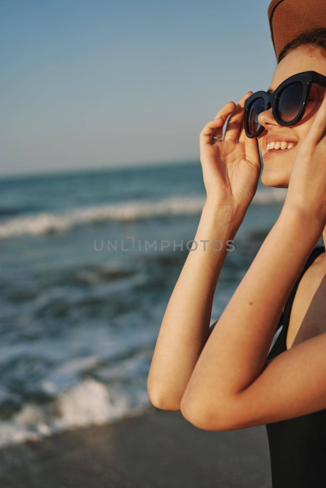cheerful woman in sunglasses and a hat by the ocean walk summer by Vichizh