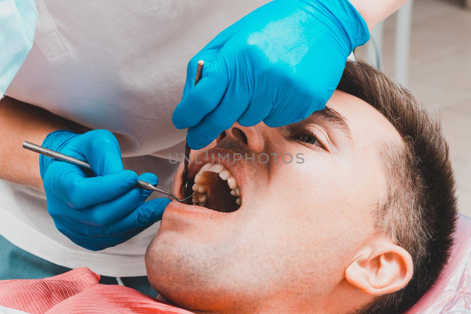 Dental clinic, the patient sits in a dental chair with his mouth wide open, the dentist assesses the condition of the teeth and makes a diagnosis.2020