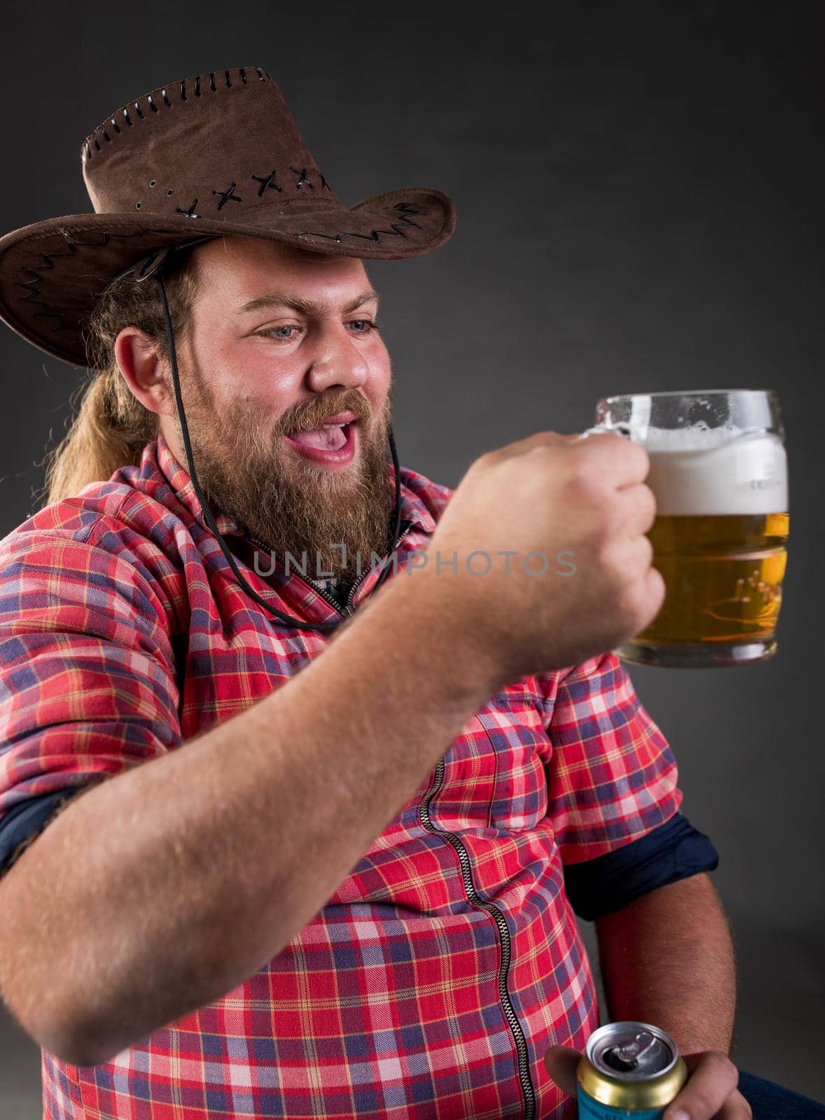 Portrait of funny young man drinking beer from mug in studio